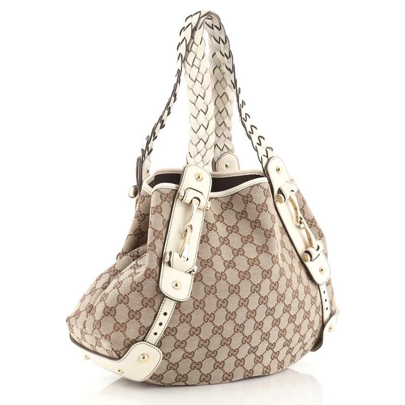 This Gucci Pelham Shoulder Bag GG Canvas Medium, crafted in neutral GG canvas, features braided leather handles, signature horsebit accents, and gold-tone hardware. Its wide top opening showcases brown fabric interior with zip pocket. 

Estimated