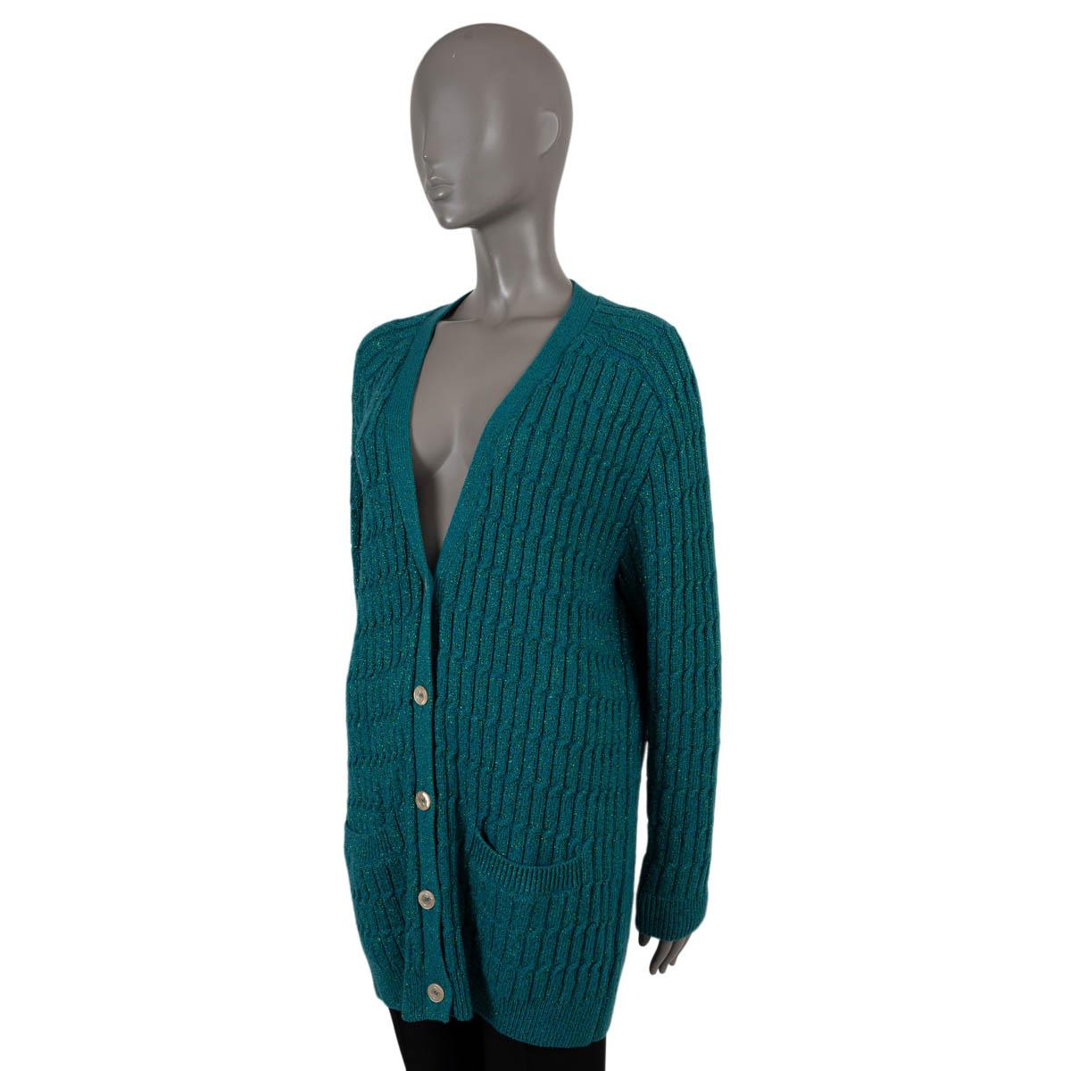 100% authentic Gucci oversized, long glitter v-neck cable knit cardigan in petrol wool (35%), viscose (26%), polyamide (24%), cashmere (9%) and metallized polyester (6%). The design features two front pockets and opens with five nude shiny buttons.