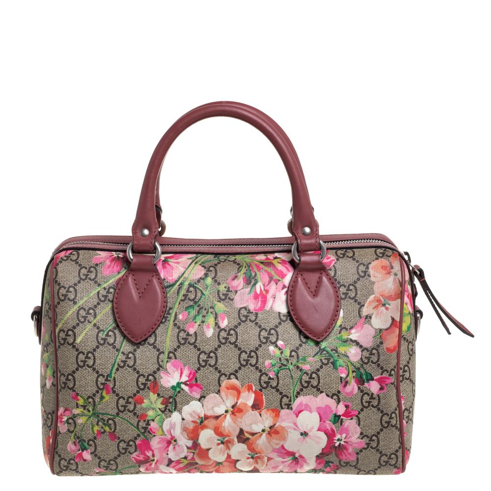 This Gucci Boston bag is designed in a GG Blooms Supreme canvas body and enhanced with leather trims. It features a boxy silhouette and is topped with two rolled handles. It comes secured with a zipper closure and adorned with silver-tone hardware.
