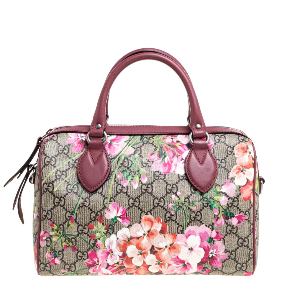 This Gucci Boston bag is designed in a GG Blooms Supreme coated canvas body detailed with leather trims. It features a boxy silhouette and topped with two rolled top handles. It comes secured with a zipper closure and fitted with a detachable