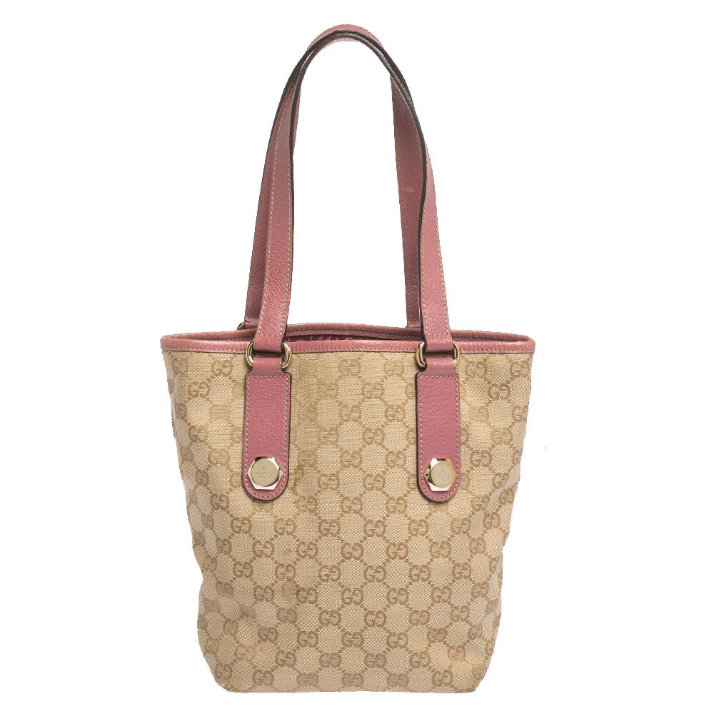 Crafted from beige GG canvas and pink leather, this open tote from Gucci is designed with minimal style details but with high attention to craftsmanship so that it may assist you with durability. The spacious interior of the bag is lined with fabric