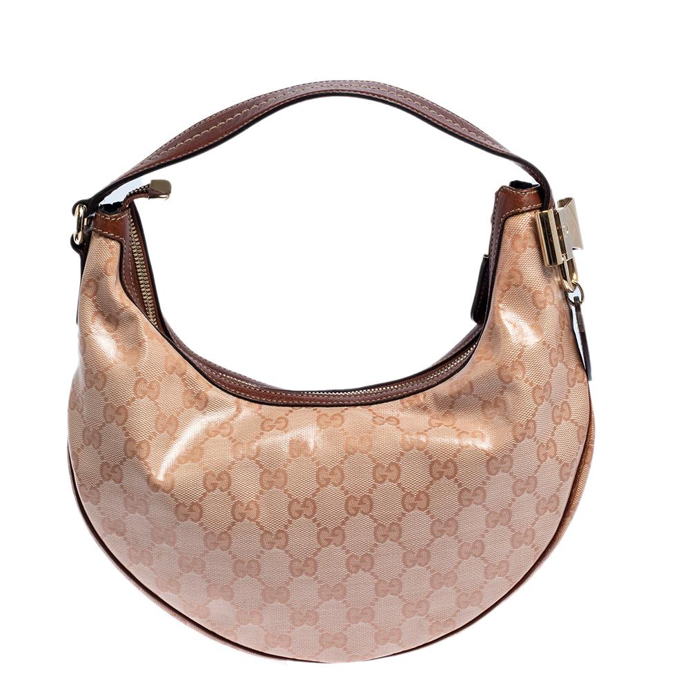 Este bolso Duchessa de Gucci está confeccionado en lona recubierta de cristal GG, así como en piel, y tiene un detalle de lazo metálico en el lateral. Lleva un asa de piel y el cierre superior con cremallera se abre a un espacioso interior forrado