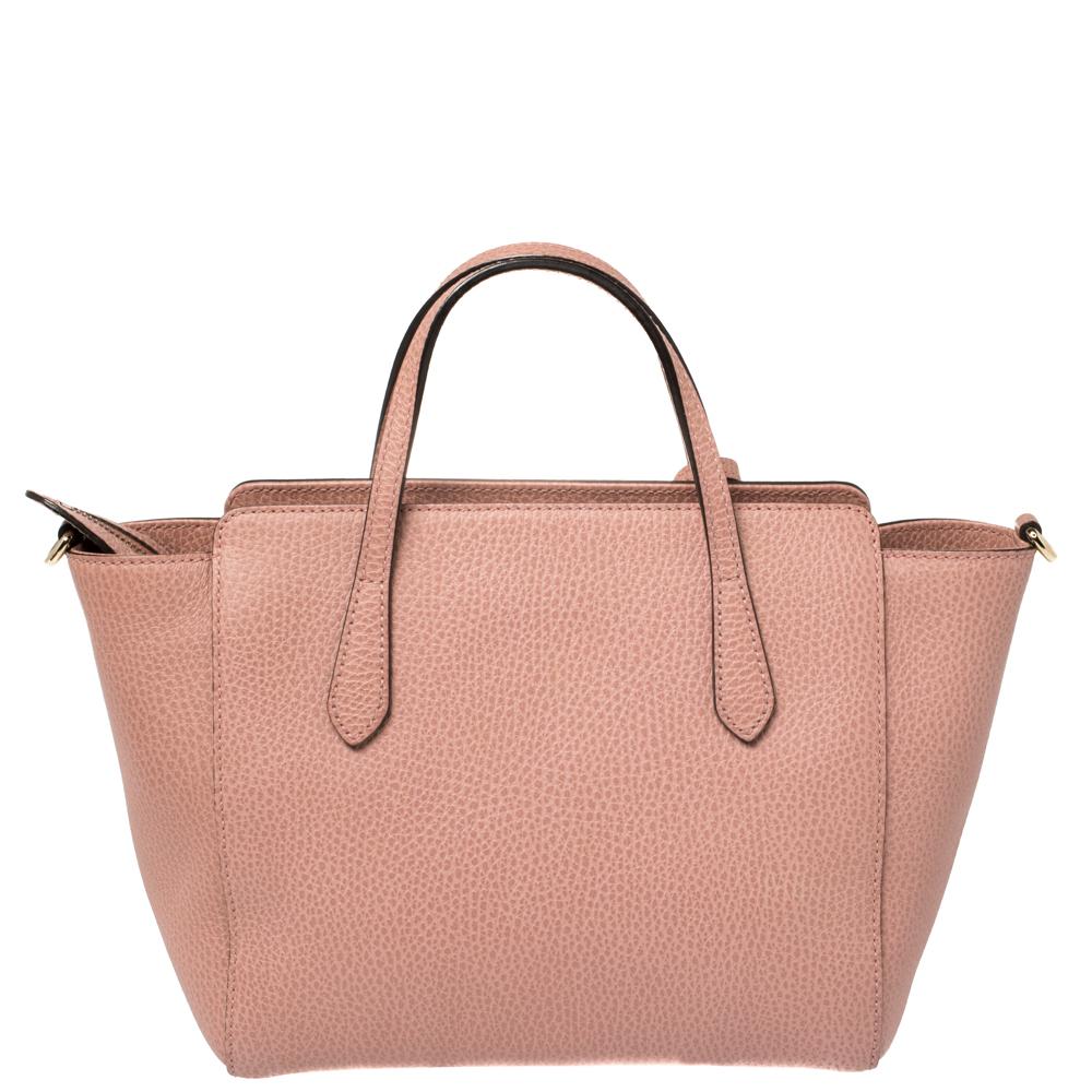Italian made, this Gucci Swing tote is all you need to make an impressive style statement. The pink creation comes crafted from quality leather and designed with two handles that carry an attached GG tag. The canvas-lined interior is spacious enough
