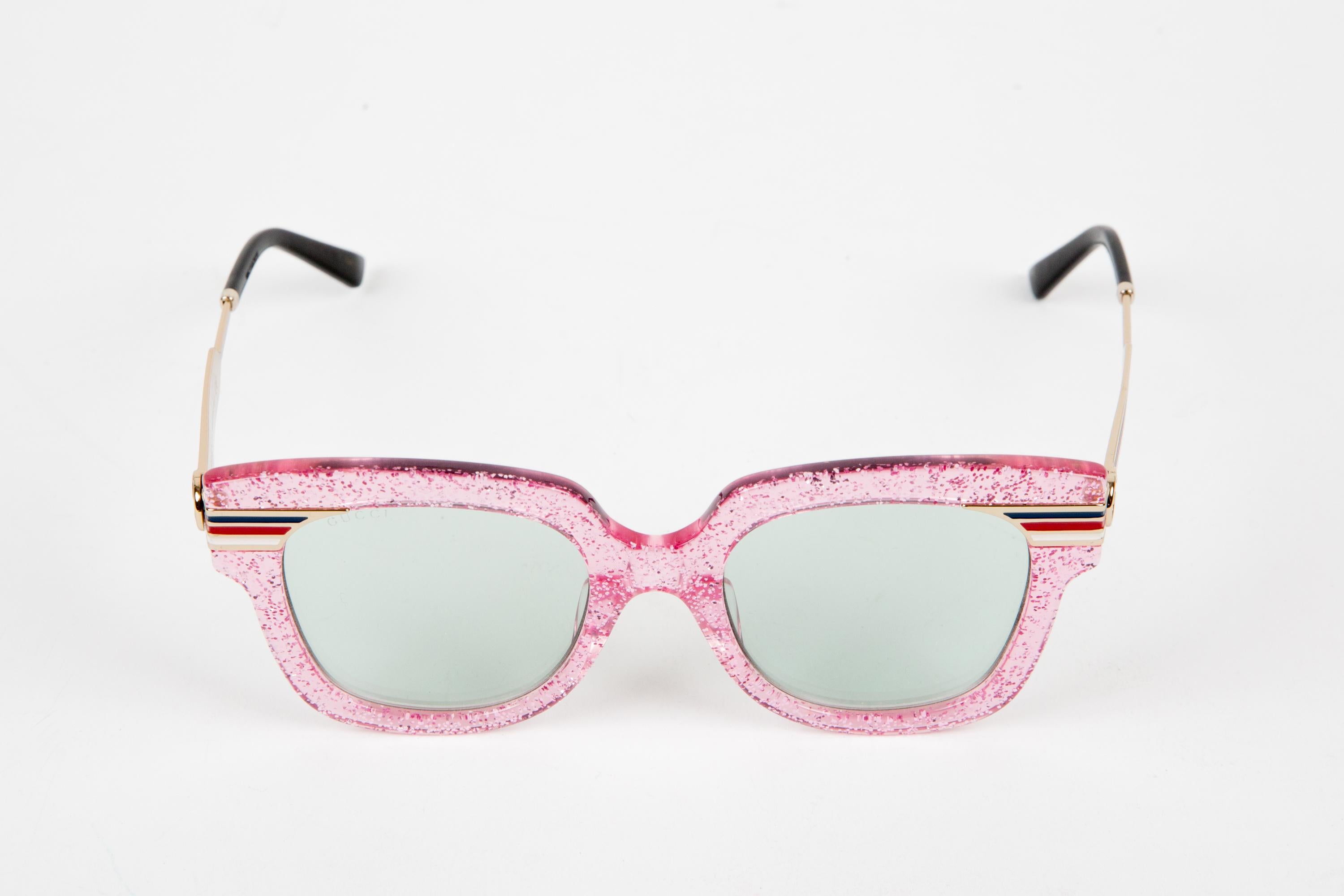Gucci Pink oversize-frame acetate sunglasses featuring pink glitter oversize-frame, metal logo-engraved arms.  100% acetate.
Circa 2000s. 
Arm Length 6.2in. (16 cm)
Lens length:1.9in. (5cm)
Total width: 5.7in. (14.5cm)
In good vintage condition.