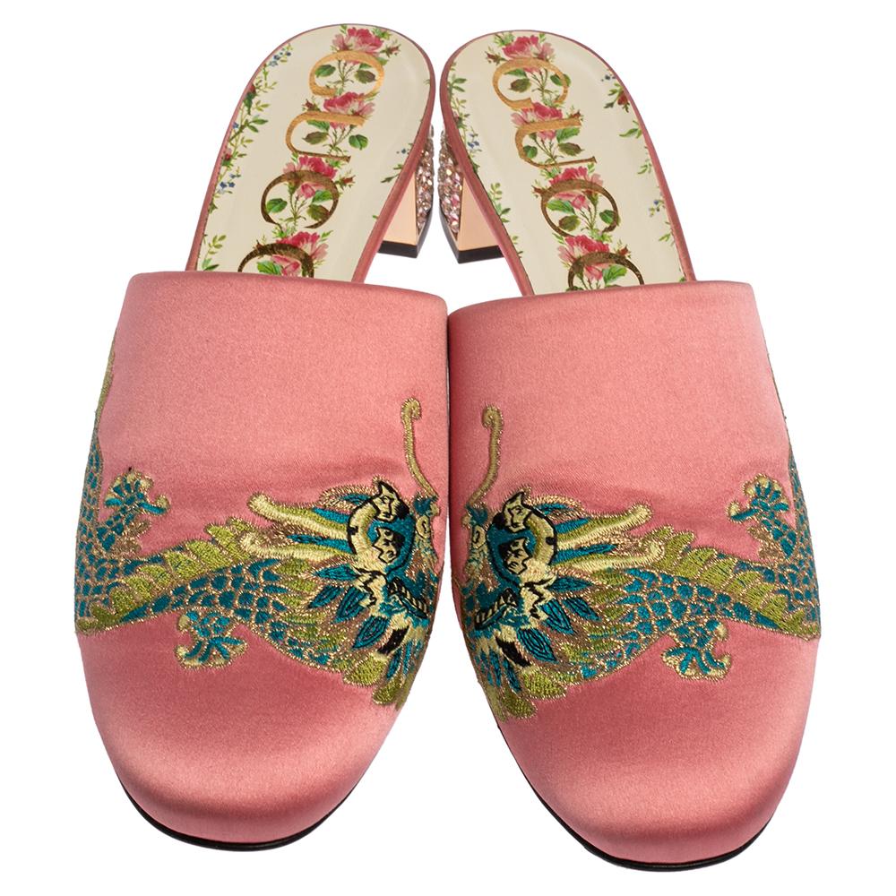 These Gucci mules will make a grand addition to your closet. These shoes are enhanced by a pretty embroidery on the vamps. Featuring a plush satin body and embellished heels, these pink mules are a note on modern sophistication.

Includes: Original