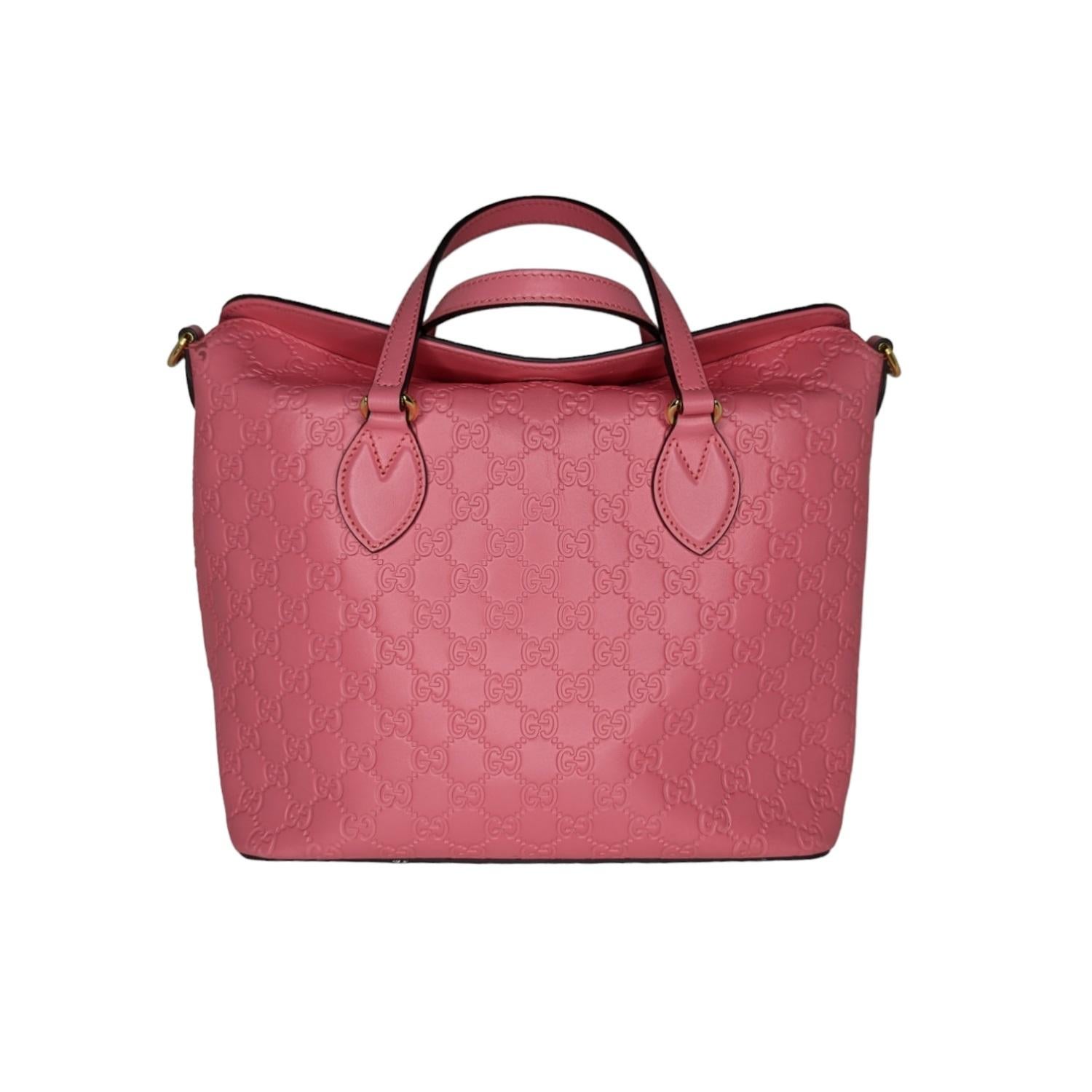 This stylish tote is finely crafted of Guccissima monogram-embossed leather in pink. The tote features thin and sturdy leather strap top handles, and an optional, adjustable shoulder strap with polished gold hardware. The top opens to a blush beige