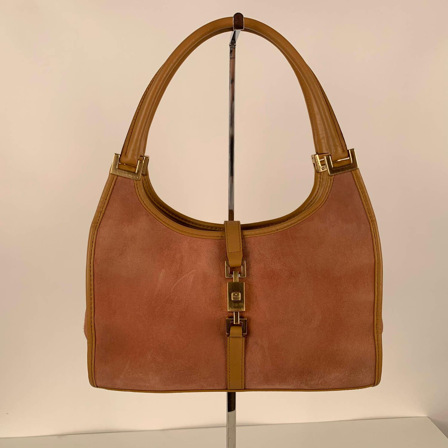GUCCI stirrup hobo crafted in pink suede with tan leather trim. Gold metal hardware. Fold over strap with push closure on the front. Beige monogram fabric lining. 1 side zip pocket inside. 'GUCCI - Made in Italy' tag inside (with serial number on