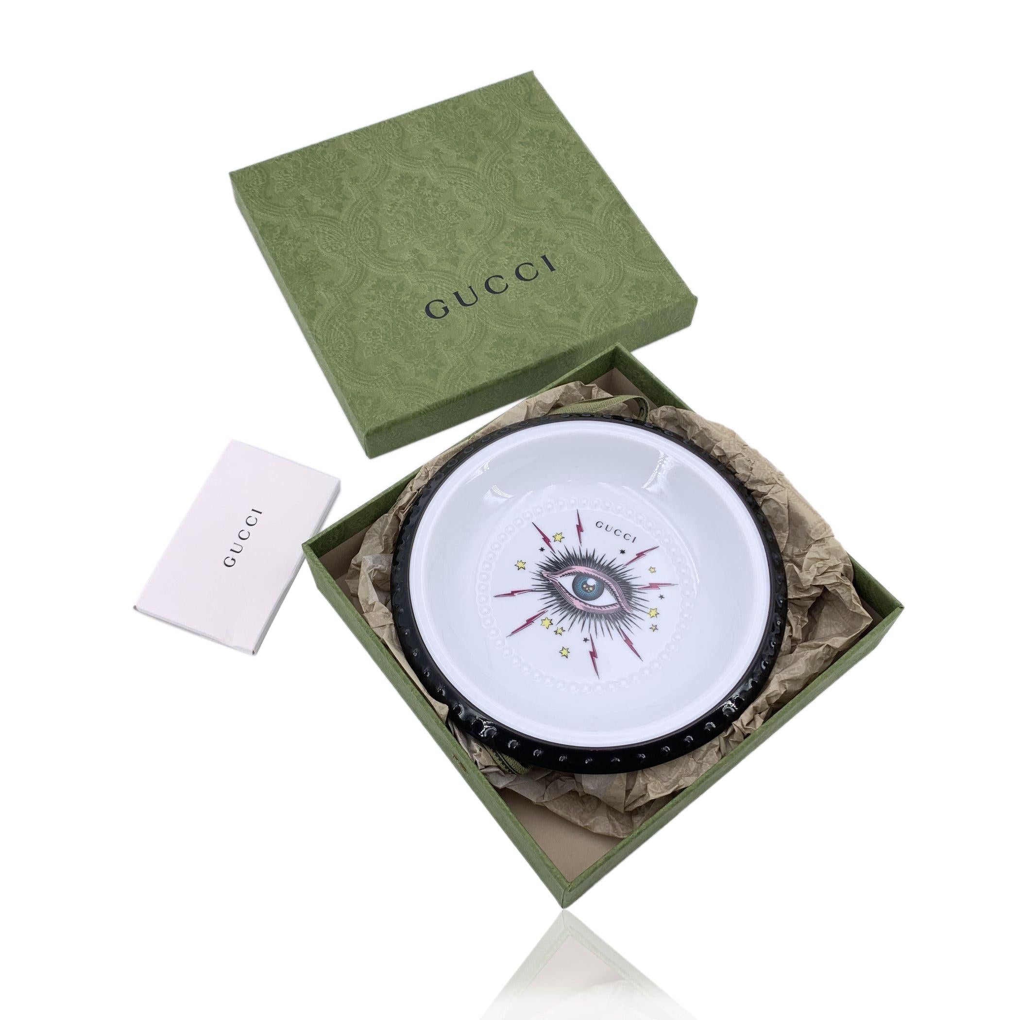 Esta exquisita bandeja decorativa Gucci es una fusión perfecta de artesanía atemporal y diseño atrevido, producida por el renombrado fabricante italiano de porcelana 