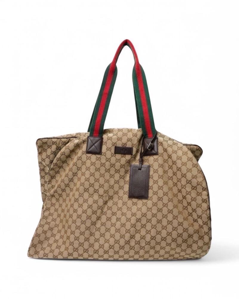 Porta abiti firmato Gucci, realizzato in tela nella fantasia classica GG Supreme con rifiniture in pelle e hardware argento. Doté d'une fermeture centrale à glissière, il est intérieurement revêtu d'un tissu en nylon de couleur marron, très
