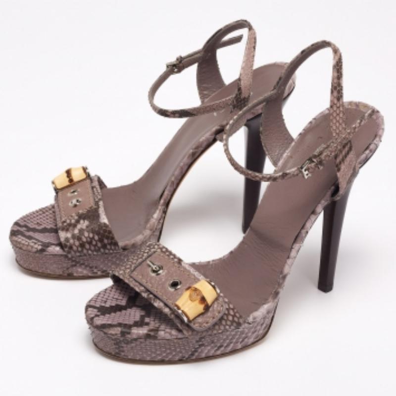 This classy pair of sandals from Gucci looks even better on the feet. The shoes have a python leather exterior added with open toes, bamboo accents, and ankle closure. They are lifted on platforms and 13 cm heels.