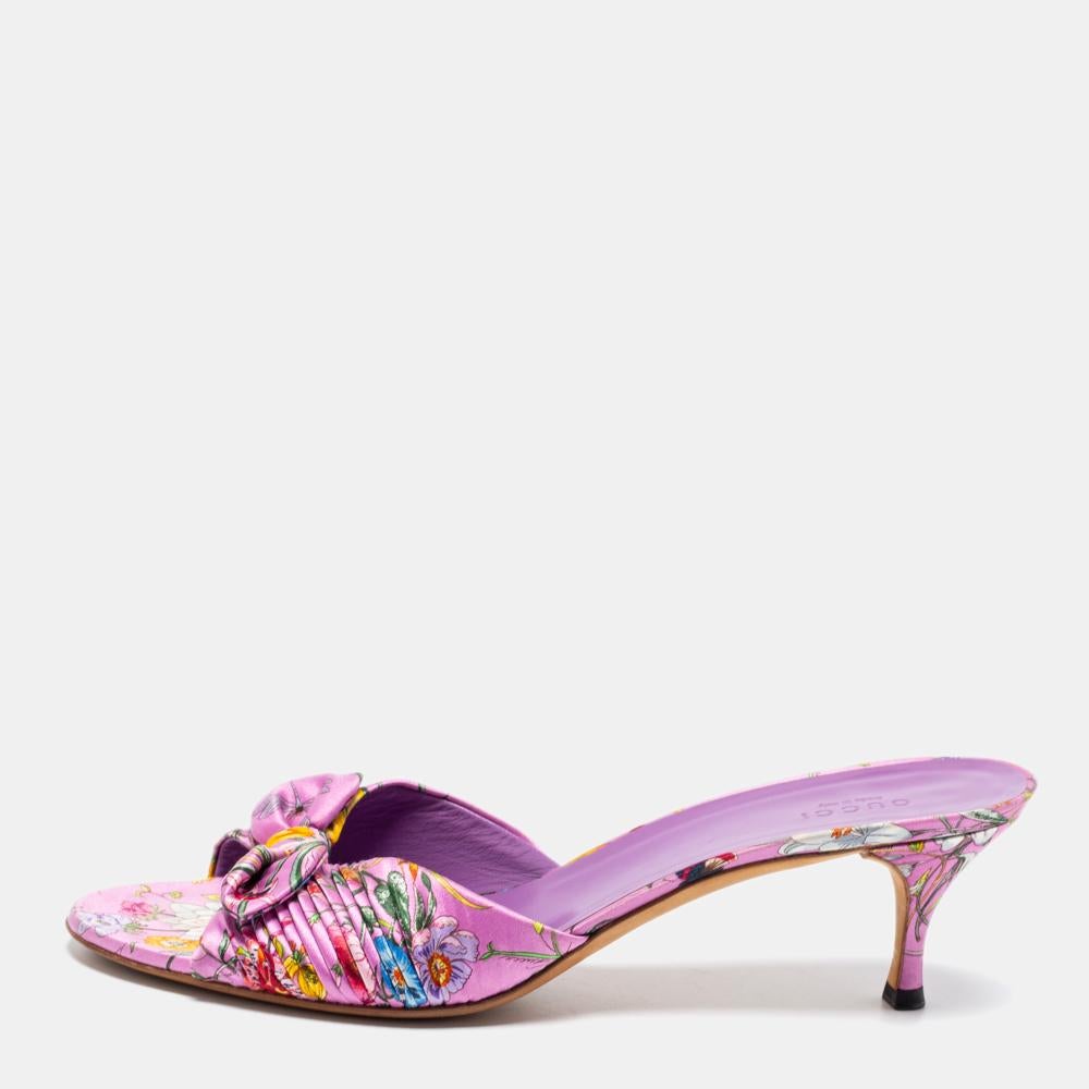 Walk stylishly as you flaunt your look in these beautiful slide sandals from the House of Gucci. Designed using purple floral-printed satin, these slides are embellished with a bow accent on the front. They are finished with 6 cm heels for a classy