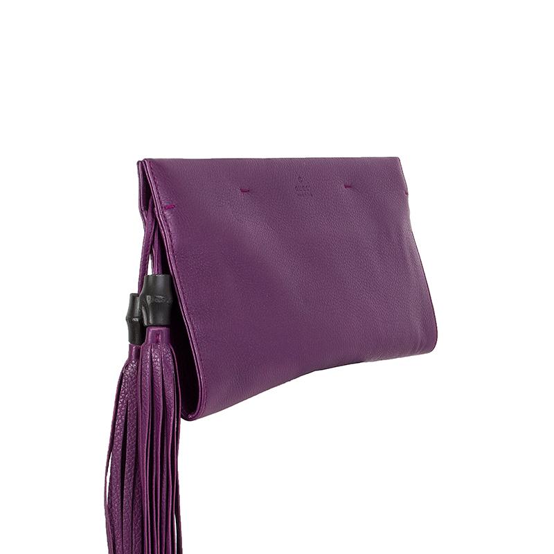 Gucci 'Nouveau' clutch in grape purple grained leather with bamboo tassels. Closes two magents on top. Lined in beige leather with a zipper pocket against the front and back. Has been carried and is in excellent condition.

Height 16.5cm