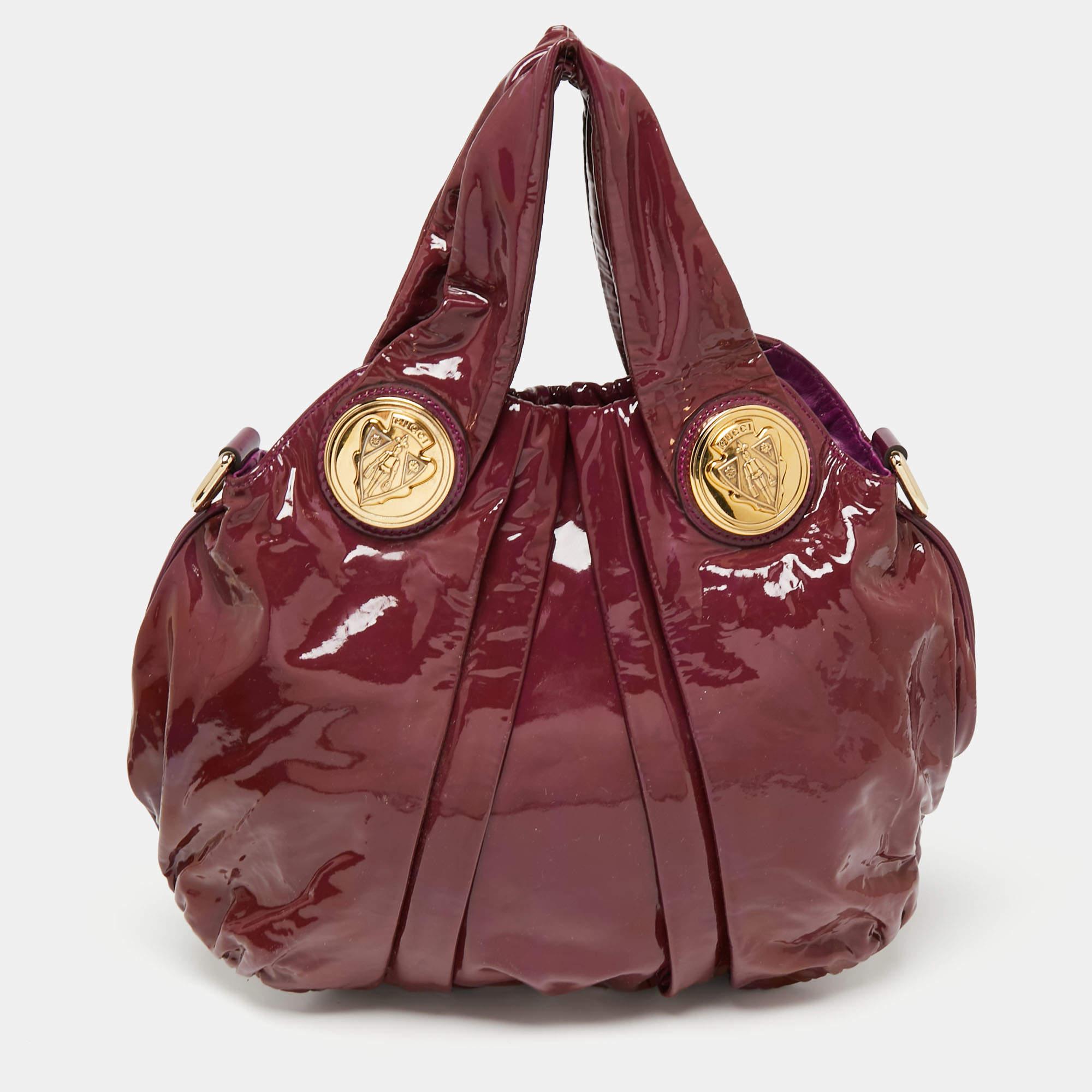 This Gucci hobo is built for everyday use. Crafted from patent leather, it has a classic-look exterior and is fitted with two top handles and a shoulder strap. The interior is sized spaciously and the hobo is complete with the signature emblems.

