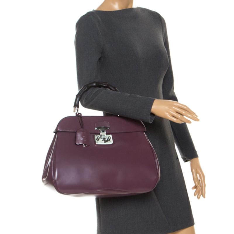 Featuring the iconic Lady Lock, this top handle bag is from Gucci. This bag is crafted from purple patent leather and features a bamboo top handle. The push lock closure opens to a suede-lined interior that houses two open compartments. Carry this