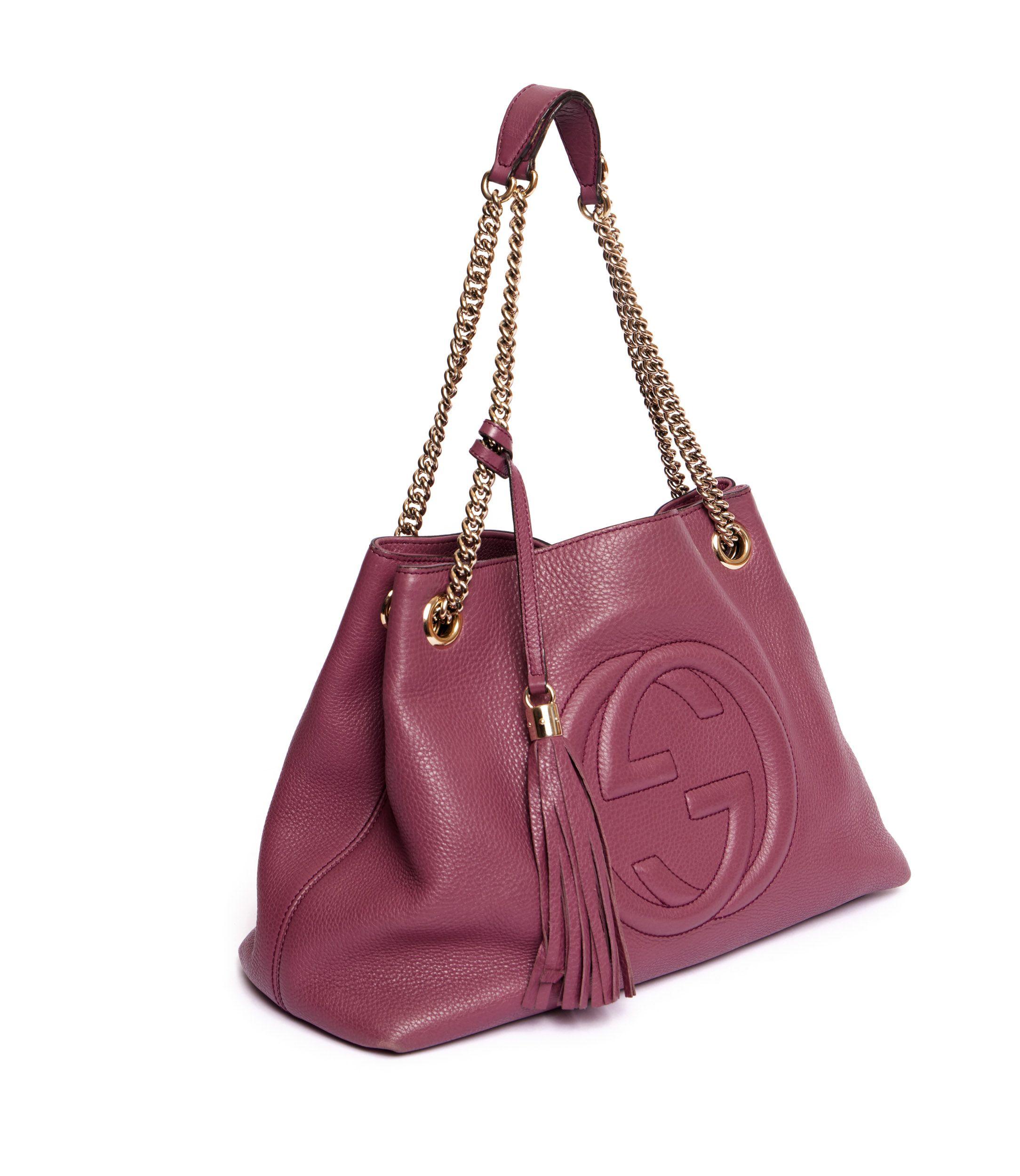 Gucci large purple pebbled leather hobo bag. On front if the bag is a large GG logo imprinted on the leather. It comes with a light gold tone metal chain attached to it is a tassel dangle. It is preowned and shows minor wear at the edges. The bag