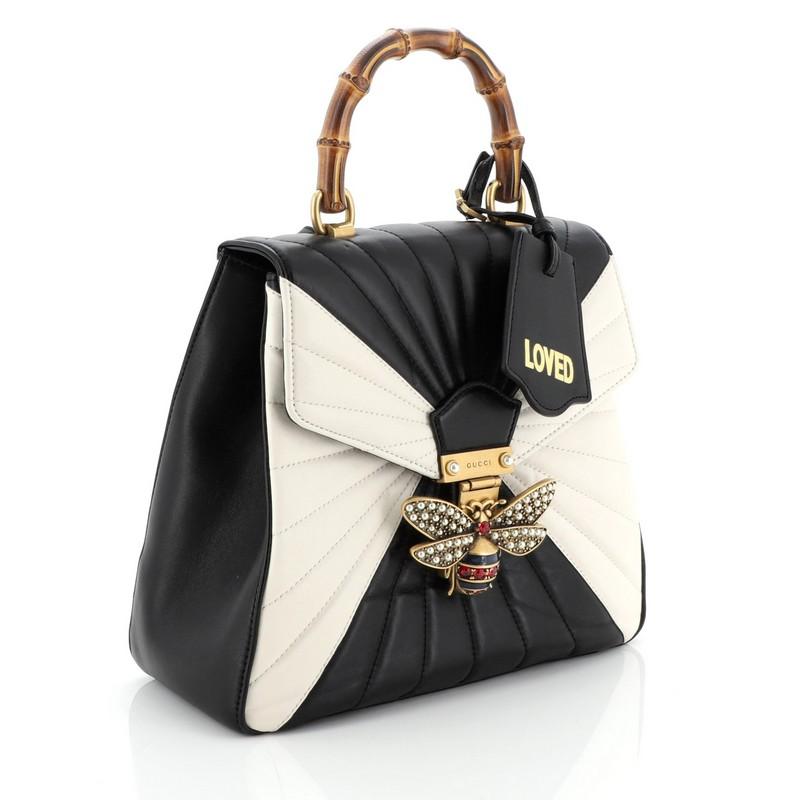 This Gucci Queen Margaret Top Handle Backpack Multicolor Quilted Leather Small, crafted from multicolor, black and white quilted leather, features a bamboo top handle, adjustable backpack straps, bejeweled bee on its flap, and aged gold-tone