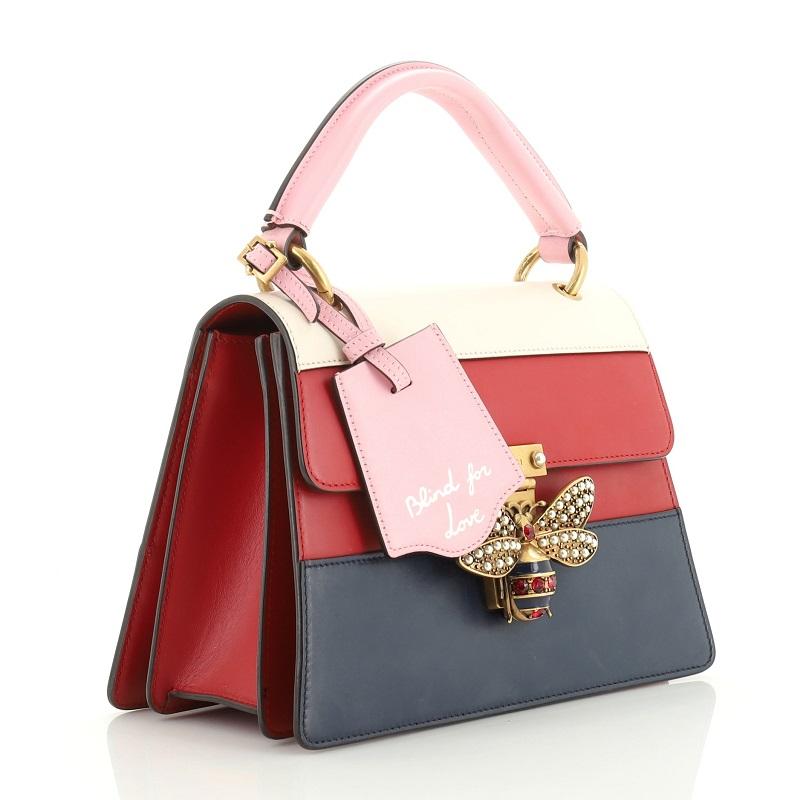 This Gucci Queen Margaret Top Handle Bag Colorblock Leather Small, crafted from multicolor, blue, blue and red leather, features a leather top handle, bejeweled bee on its flap, and aged gold-tone hardware. It opens to a neutral microfiber interior