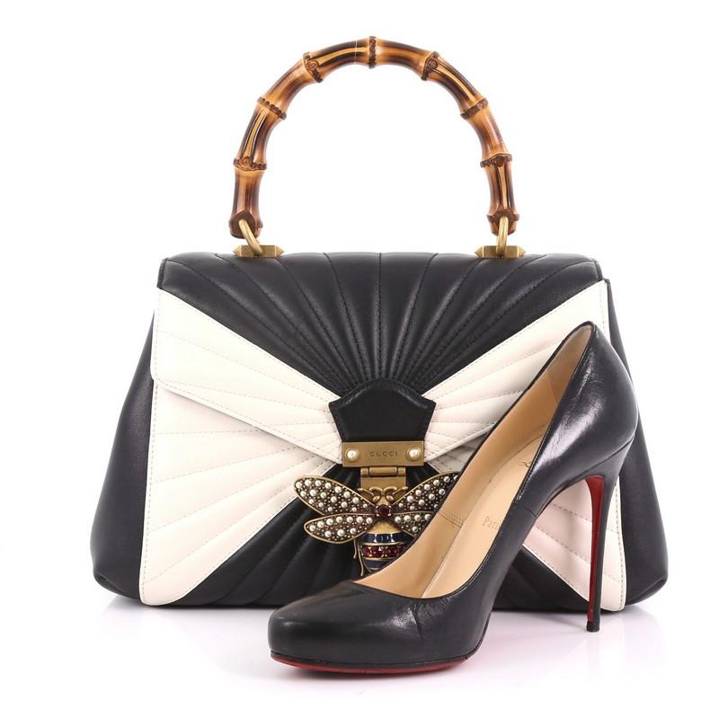 This Gucci Queen Margaret Top Handle Bag Multicolor Quilted Leather Medium, crafted from black and white quilted leather, features a bamboo top handle, a bejeweled bee as a symbol of wisdom and love on its flap, and aged gold-tone hardware. It opens