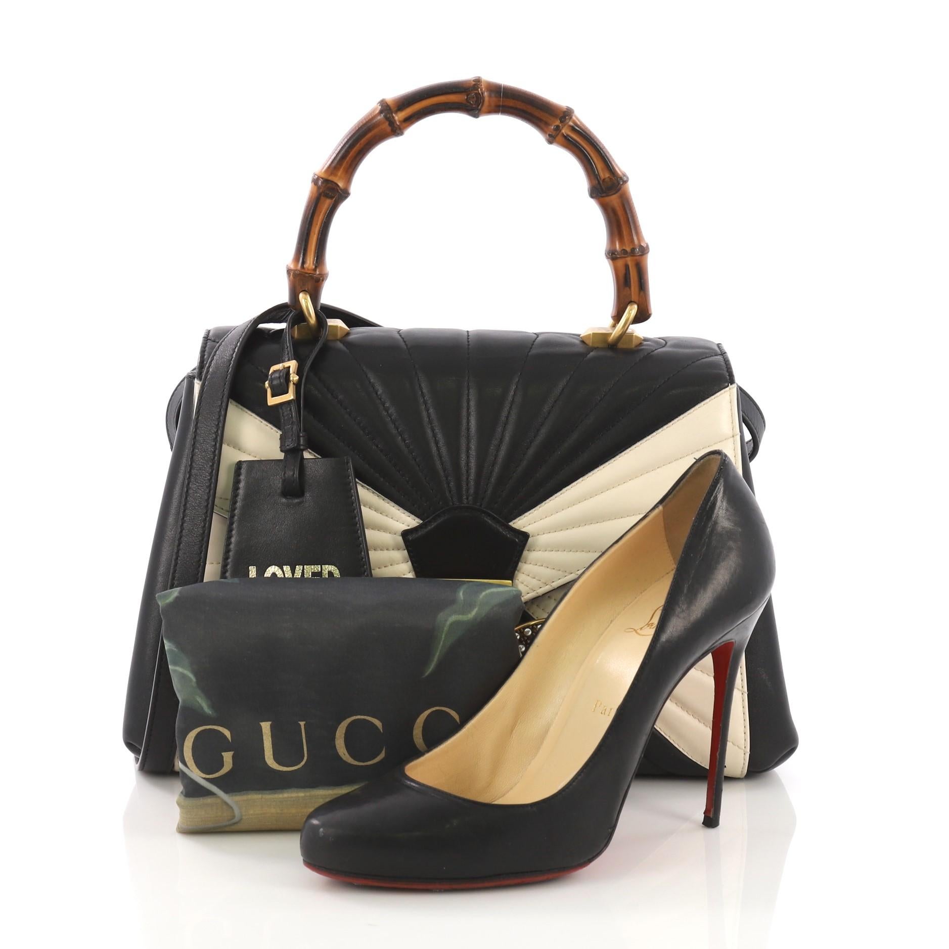 This Gucci Queen Margaret Top Handle Bag Multicolor Quilted Leather Medium, crafted from black and white multicolor quilted leather, features a bamboo top handle, bejeweled bee on its flap, and aged gold-tone hardware. It opens to a pink microfiber