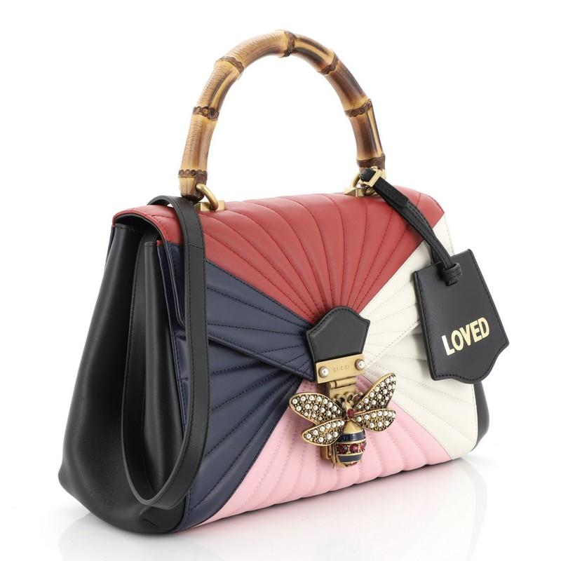 This Gucci Queen Margaret Top Handle Bag Multicolor Quilted Leather Medium, crafted from multicolored quilted leather, features a bamboo top handle, a bejeweled bee on its flap, and aged gold-tone hardware. It opens to a beige microfiber interior