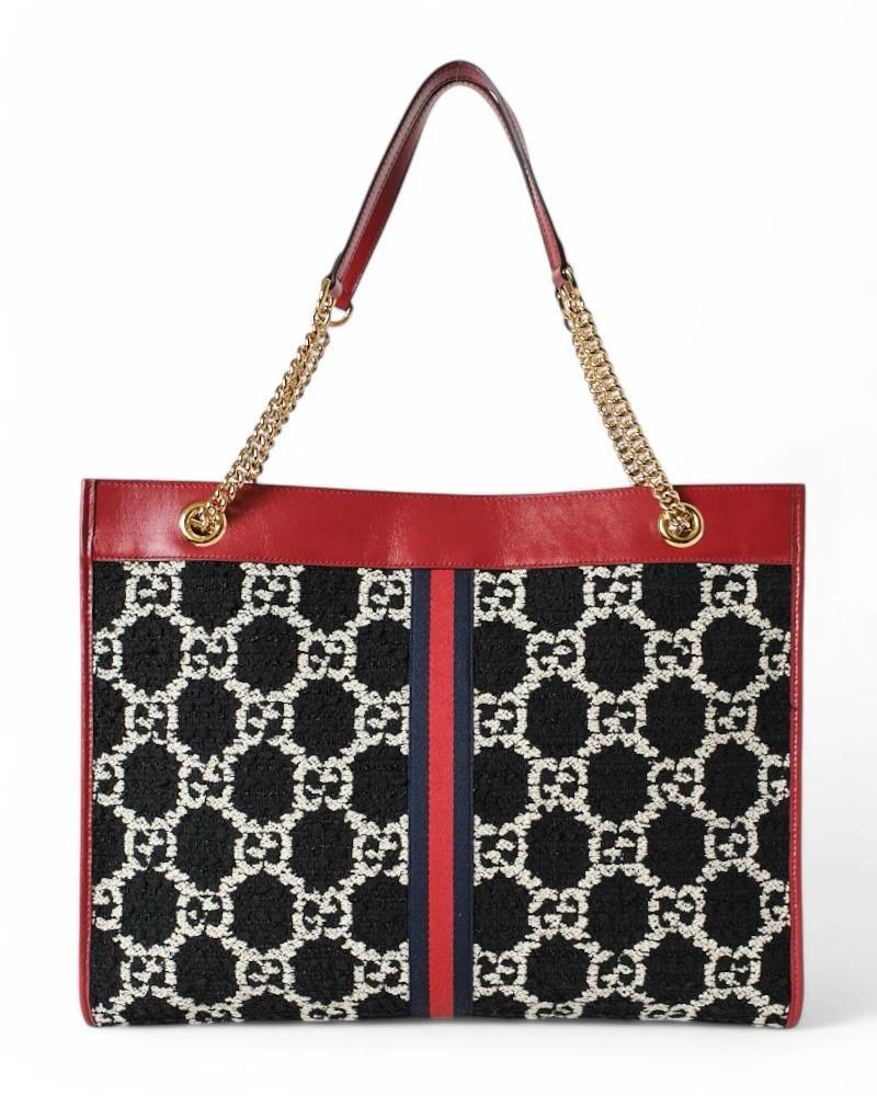 Bag  signed Gucci, model Rajah in size Large, made of black tweed with the classic GG Supreme pattern and finished with red leather and gold hardware. The bag has a central magnetic closure,  internally lined with beige suede fabric, offering ample