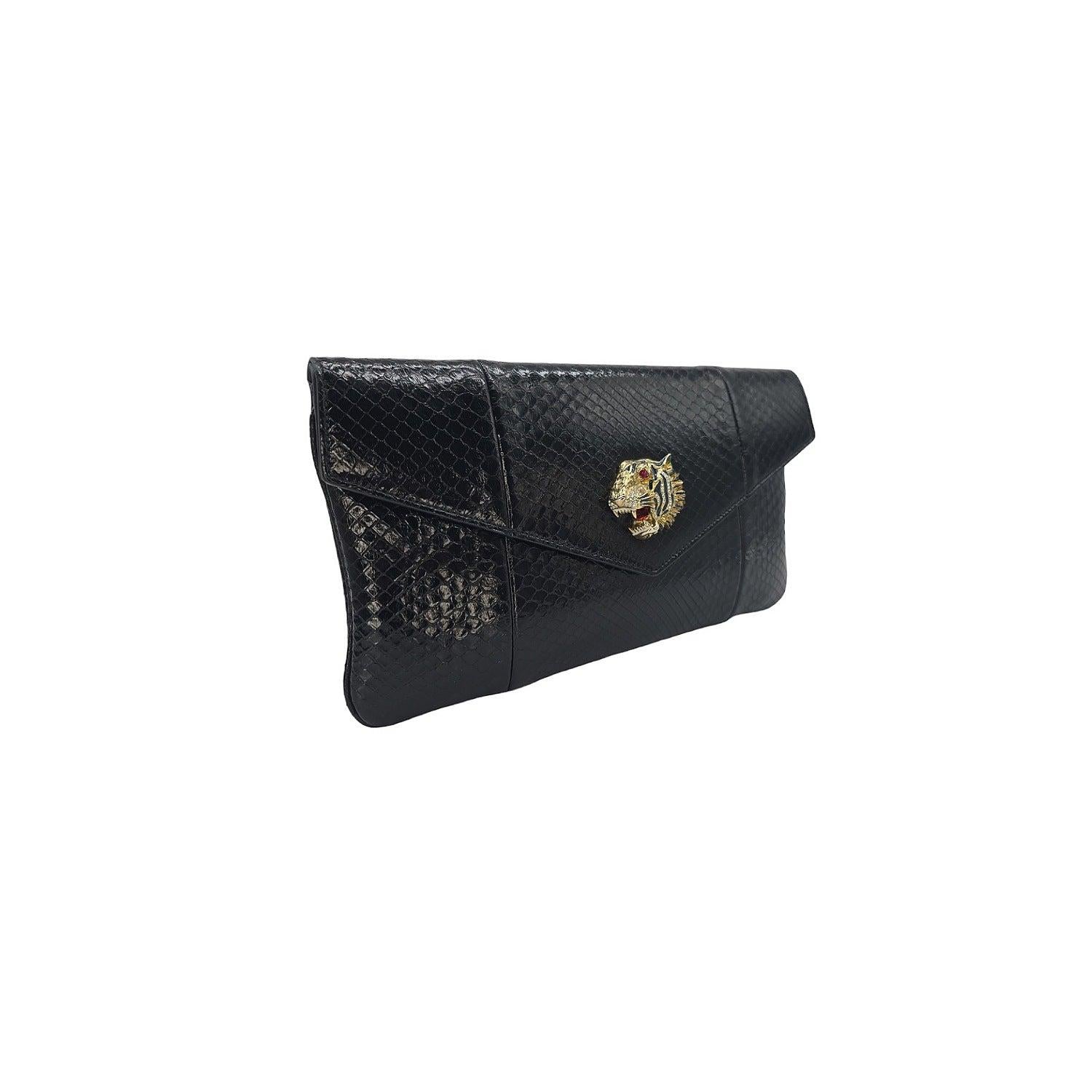La pochette enveloppe Rajah en python de Gucci est un accessoire luxueux qui respire la sophistication. Réalisée en peau de serpent noire et dotée d'un emblème en forme de tête de tigre incrusté de cristaux, cette pochette est une pièce de choix.