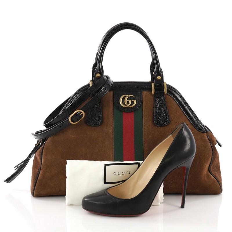 This Gucci RE(BELLE) Top Handle Bag Suede Medium, crafted from brown suede, features dual rolled leather handles, framed top design, GG interlocking logo, green and red web strap detailing, and aged gold-tone hardware. Its top zip closure opens to a