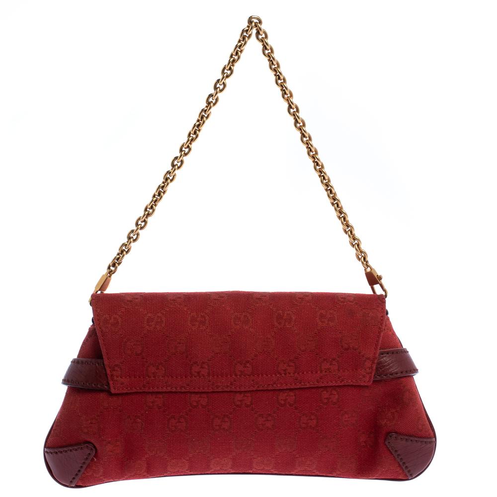 Complete a fashionable look with this beautiful Gucci shoulder bag. It is made from red-hued canvas and leather and features an exaggerated Horsebit accent in gold-tone on the front. The flap closure opens to a fabric-lined interior that will hold