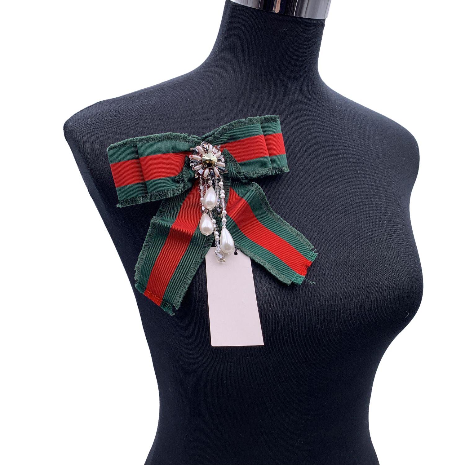 Beautiful Gucci green/red/green striped grosgrain bow brooch. Pearls and rhinestones embellishment on the front.Safety pin closure on the back. Approx. width: 5.5 inches - 14 cm. Approx. height: 6 inches - 15.2 cm. Signed 'Gucci' on back. Condition