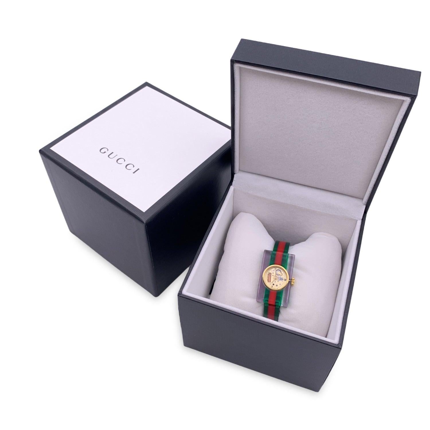 Beautiful bangle wristwatch,mod. 143.5, by GUCCI. Made of translucent green/red/green plexiglass, from the 2018 Resort collection. It features a plexiglass rectangular frame with a round gold-tone stainless steel round case. Gold metal skeleton
