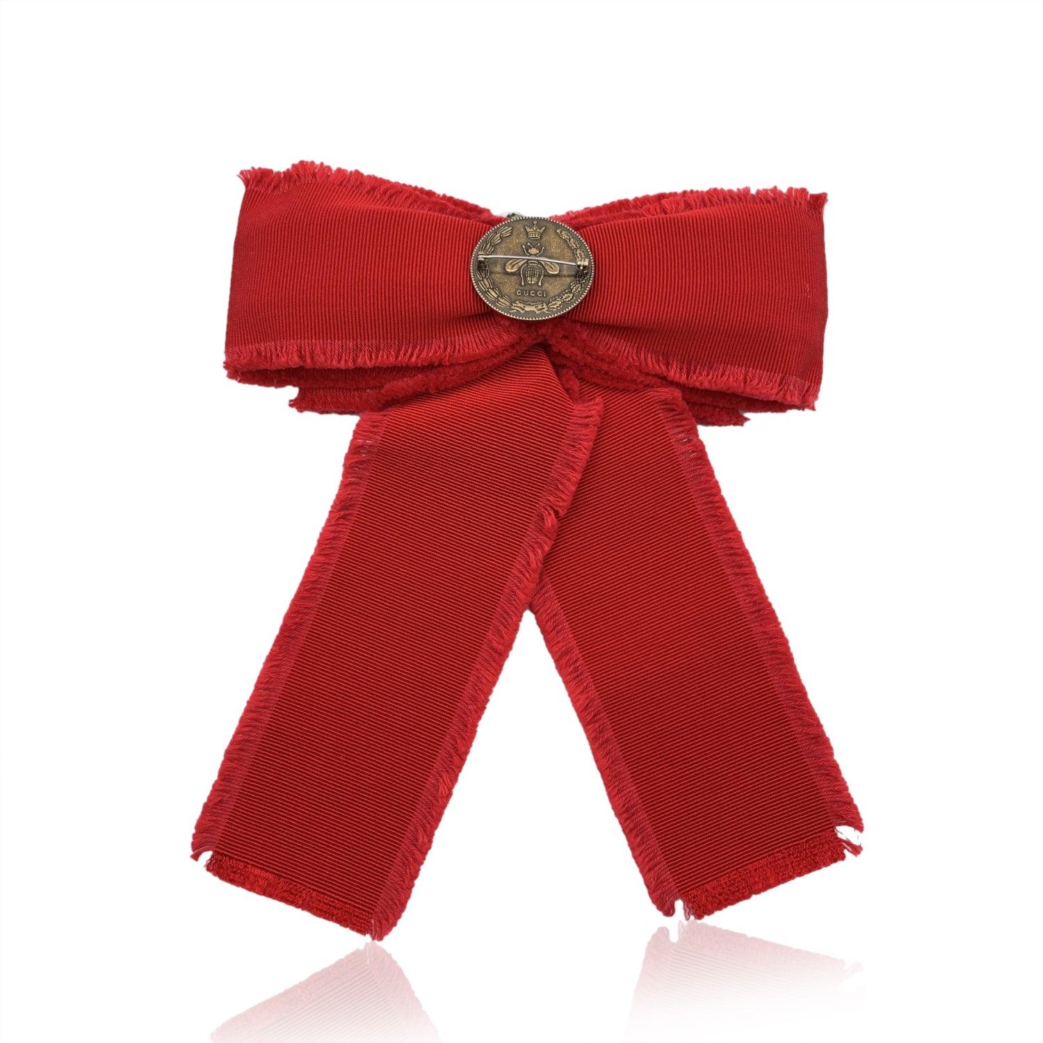 Beautiful Gucci red grosgrain bow brooch. Pearls and rhinestones embellishment on the front. Frayed edges. Safety pin closure on the back. Approx. width: 7 length - 17.7 cm. Approx. height: 8 inches - 20.3 cm. Signed 'Gucci' on back. Condition A+ -