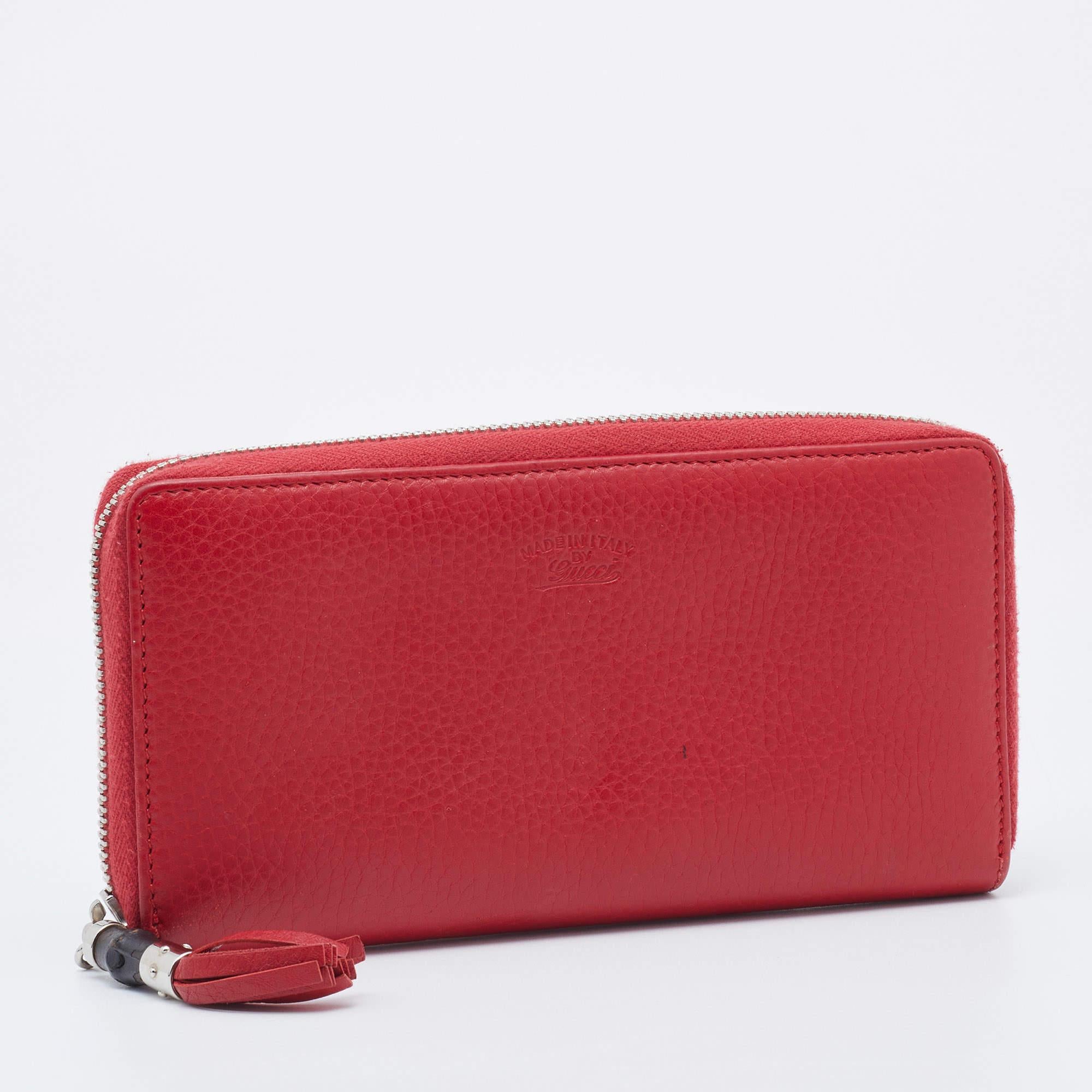 Keep it classy and chic with this minimally designed Gucci wallet. Designed in a red shade, it is crafted from leather, and it is adorned with silver-tone accents. The top zipper closure is equipped with a bamboo tassel slider and secures its