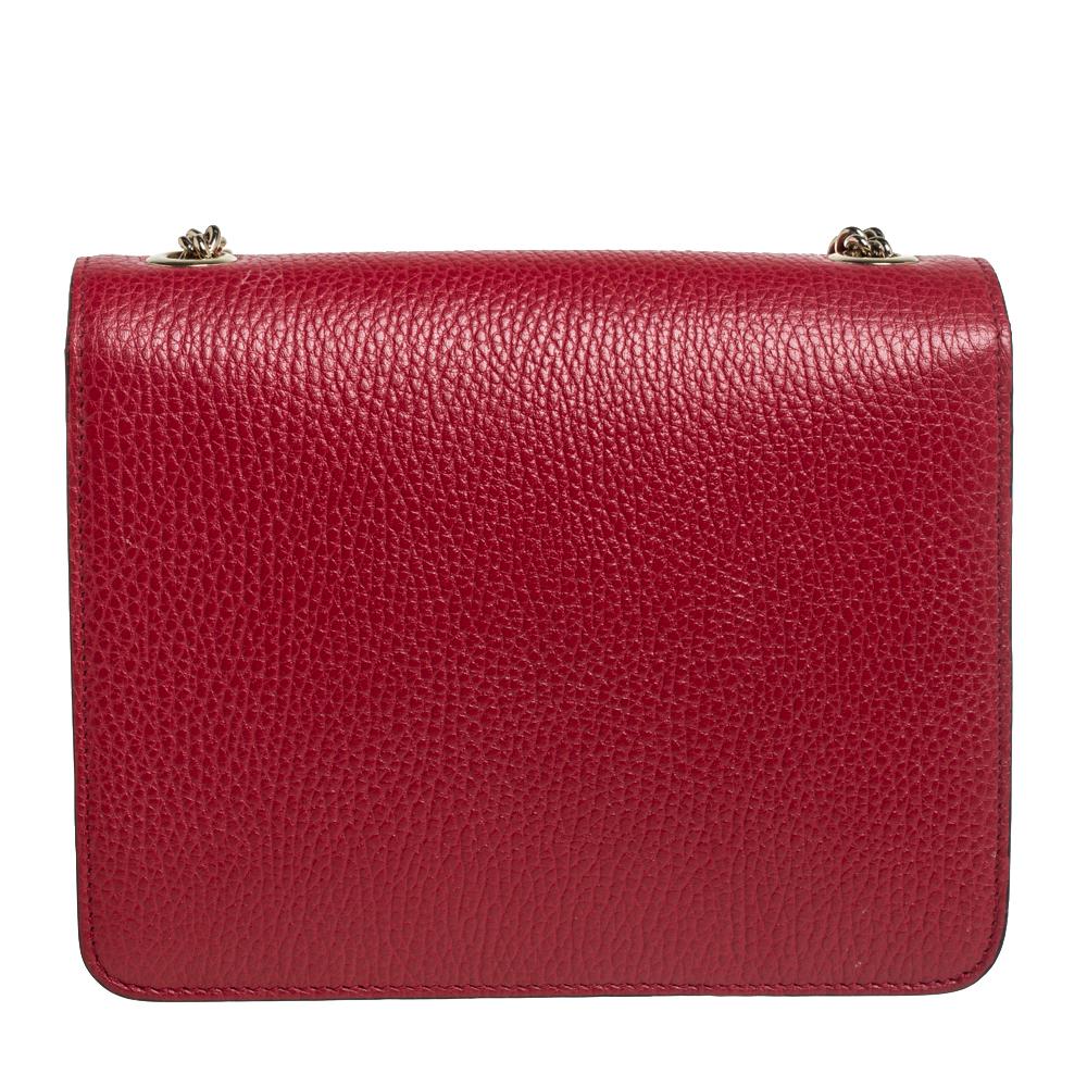 This Gucci crossbody bag is a minimal design that exhibits sophistication. Crafted from red leather, it features a structured silhouette adorned with a logo accented front flap that opens to a well-sized interior. Hold it by the slender strap and