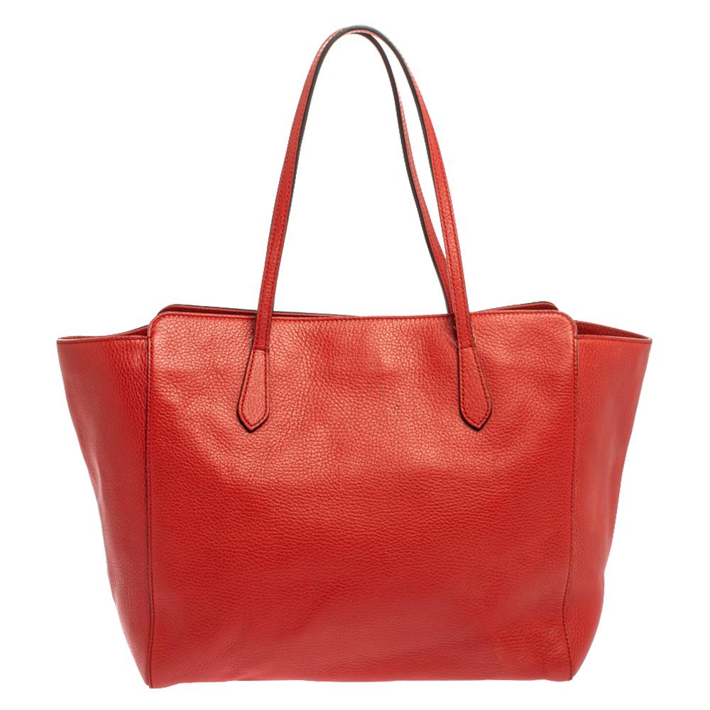 This shopper tote from Gucci is a timeless piece. The bag is crafted from luxurious red leather and has the GG logo on gold-tone on the front. It features double top handles and a fabric-lined interior with a zip pocket. The bag is sized to easily