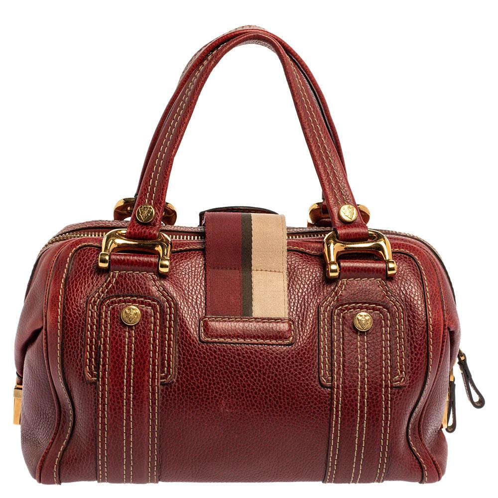 A truly posh and elegant piece to add to your collection. This Aviatrix bag by Gucci is crafted from red leather, and it is styled with a flap that carries an emblem for a lock. It also has a top zip closure, two handles, protective metal feet, and
