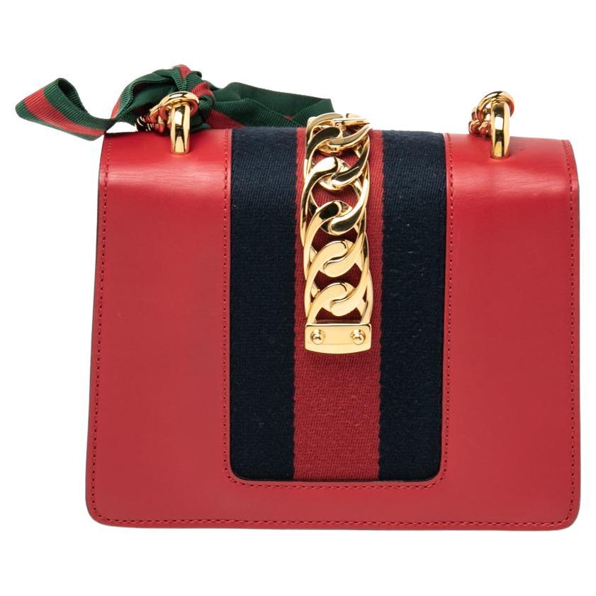 Gucci's Sylvie bag brings House codes and high-grade materials with a contemporary design. This mini Sylvie is crafted using red leather and styled with a chain-Web decorated flap and a buckle lock to secure the Alcantara interior. The bag is