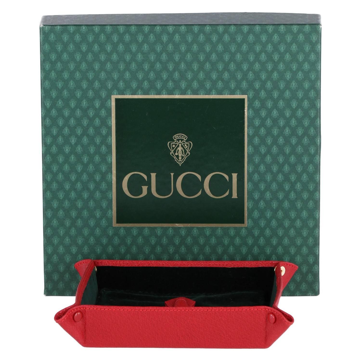 Feminine Gucci square pocket emptier in red leather and lined in green velvet. It includes a green velvet flap, decorated with a red leather bow. The item was produced in the 2000s and is in excellent conditions. It includes the original Gucci