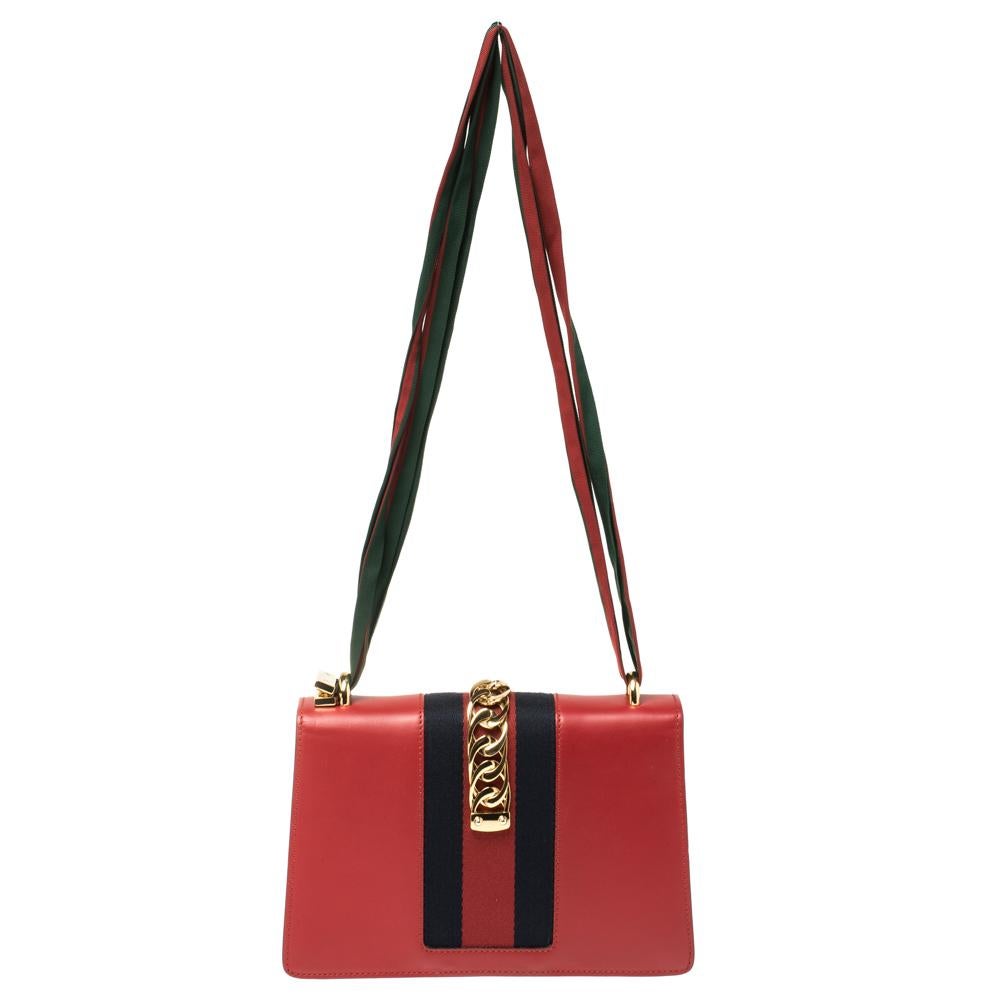 From the house of Gucci comes this gorgeous Sylvie shoulder bag that will perfectly complement all your outfits. It has been luxuriously crafted from red leather and styled with a chain-web decorated flap and a buckle lock to secure the suede