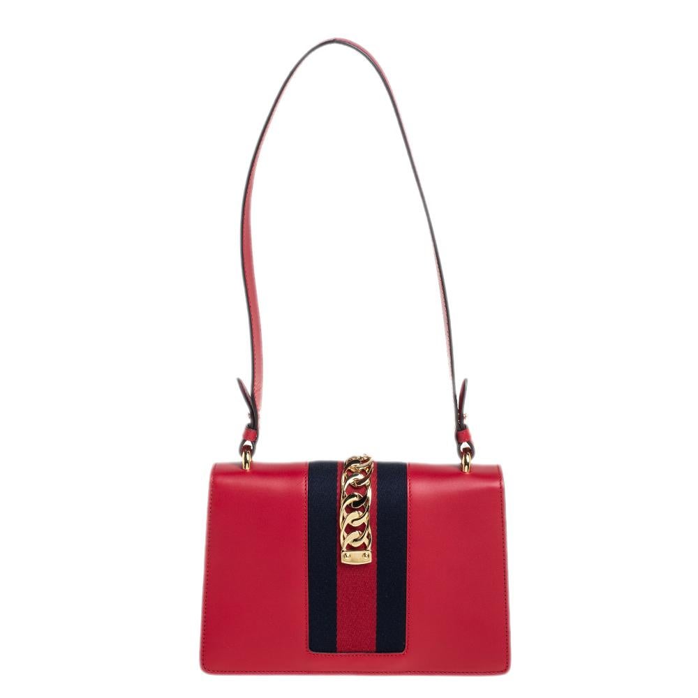 From the house of Gucci comes this gorgeous Sylvie shoulder bag that will perfectly complement all your outfits. It has been luxuriously crafted from red leather and styled with a chain-web decorated flap and a buckle lock to secure the Alcantara