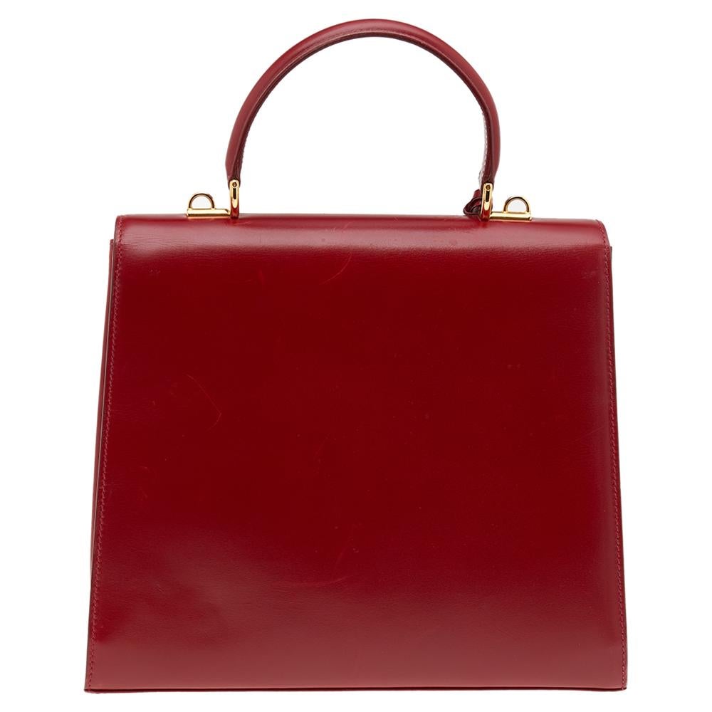 Structured neatly into a sturdy, eye-catching shape and augmented with signature detailing, this Vintage Kelly Rare Lady Lock bag from the House of Gucci will etch its way into your mind easily. It has been created using red leather and comes with a