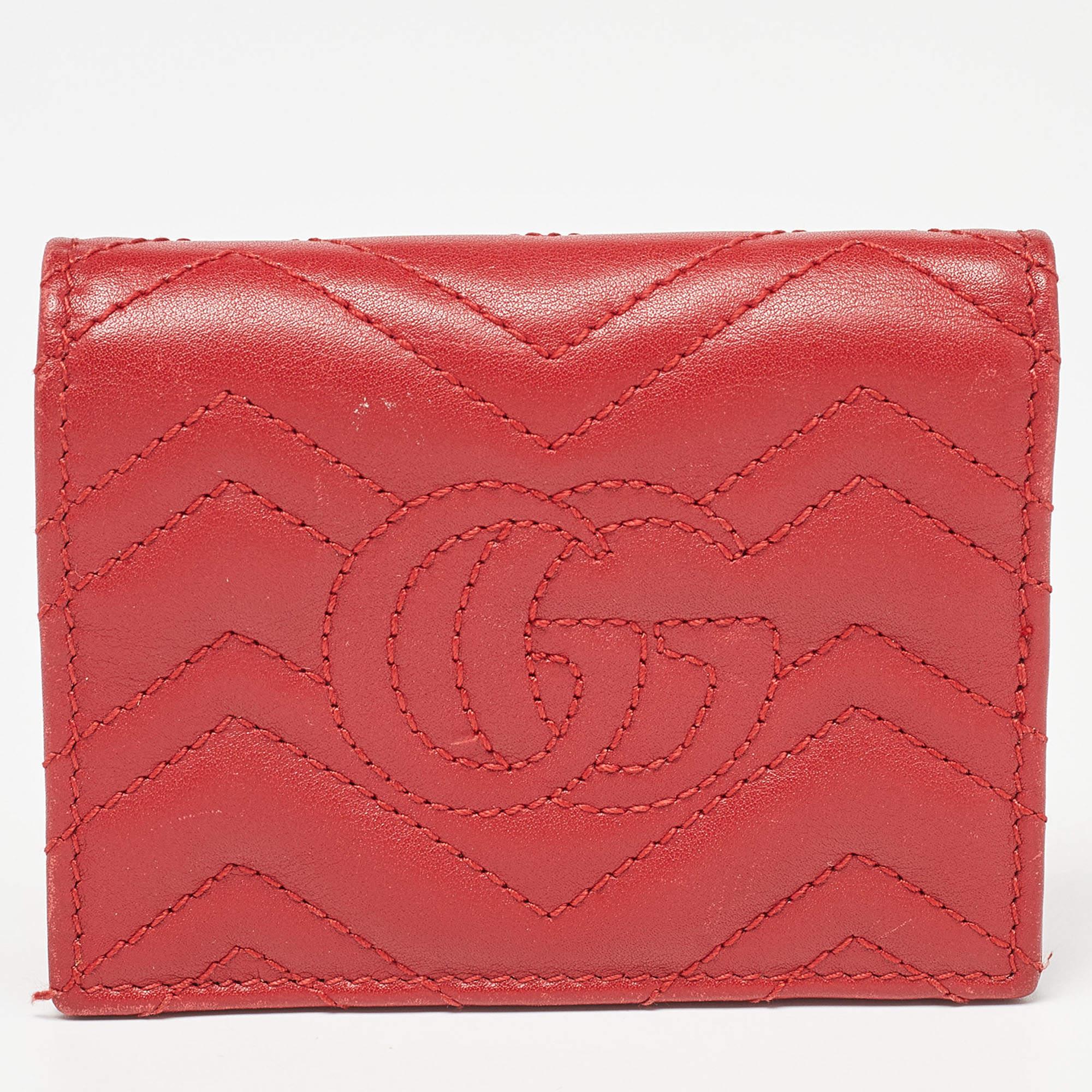 The Gucci card case is a luxurious accessory crafted from rich red matelassé leather. It features the iconic GG logo pattern, a flap closure, and multiple card slots for organization. This compact, stylish case embodies Gucci's timeless elegance and