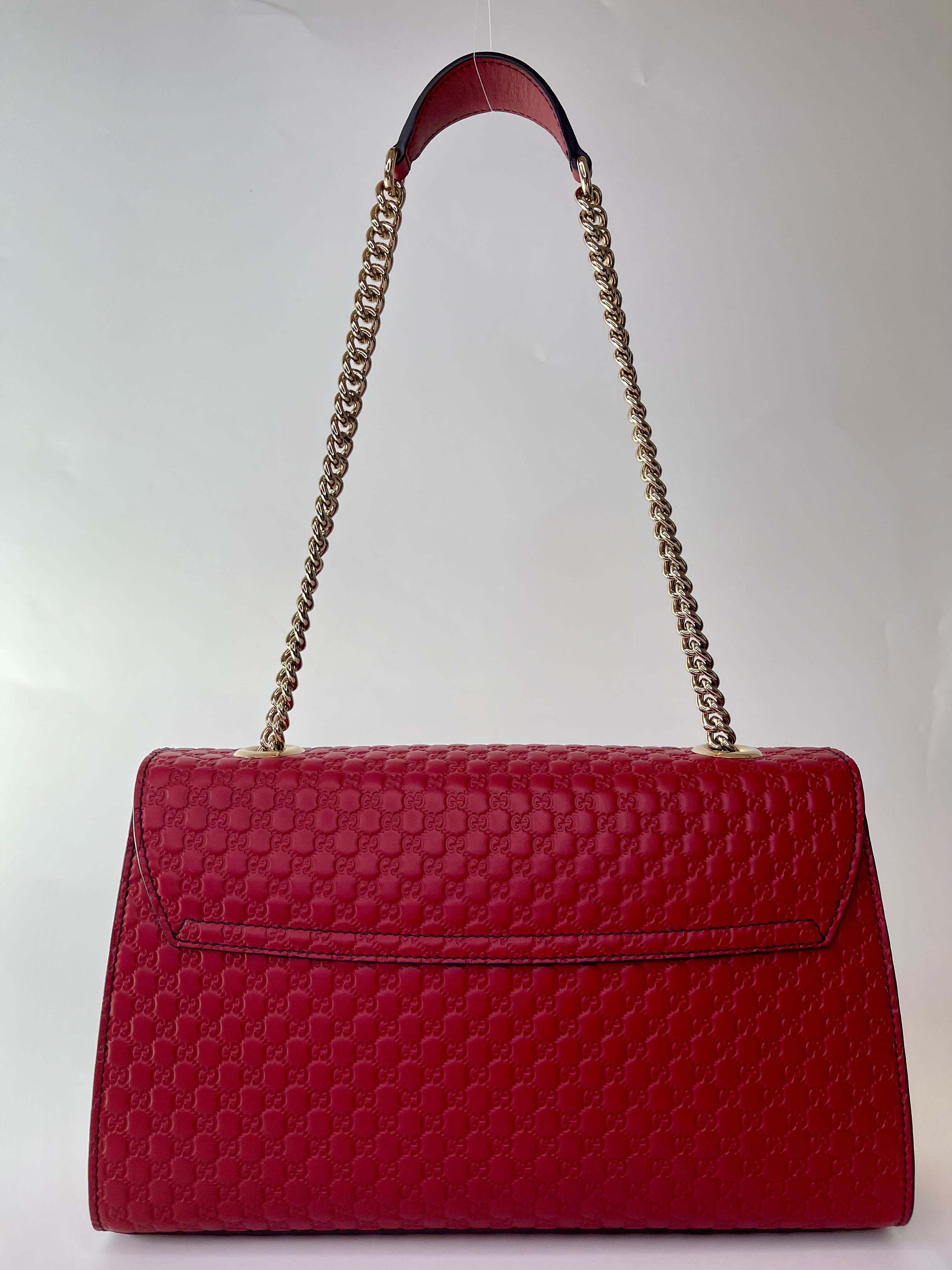 This Shoulder is made of fine Gucci GG monogram embossed leather in a deep red, featuring a light gold chain link shoulder strap with a leather shoulder pad and a crossover flap secured with a strap adorned with leather tassels and a gold horse bit