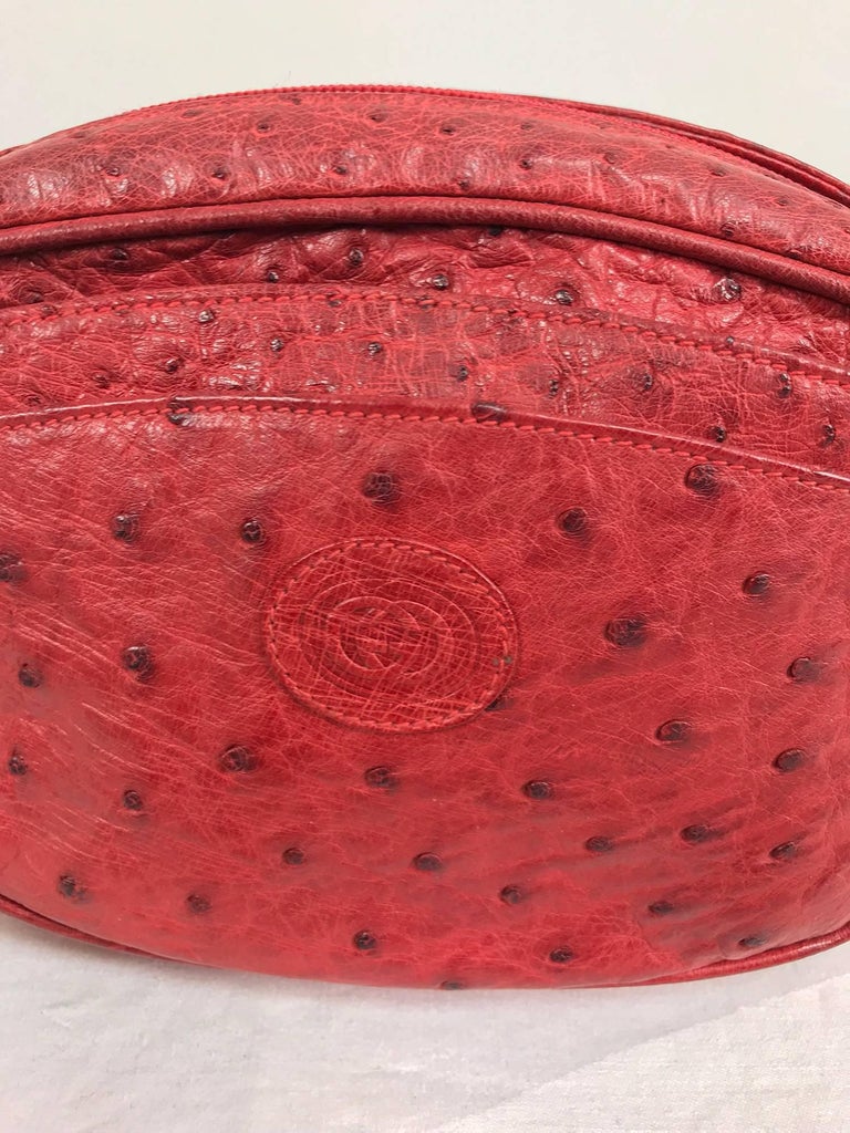 Gucci red ostrich cross body bag from the 1980s...A beautiful bag in excellent condition with a lovely patina of use...Oval bag has graduated open outside front compartments with an embossed Gucci logo at the front...Zipper closure at the top with