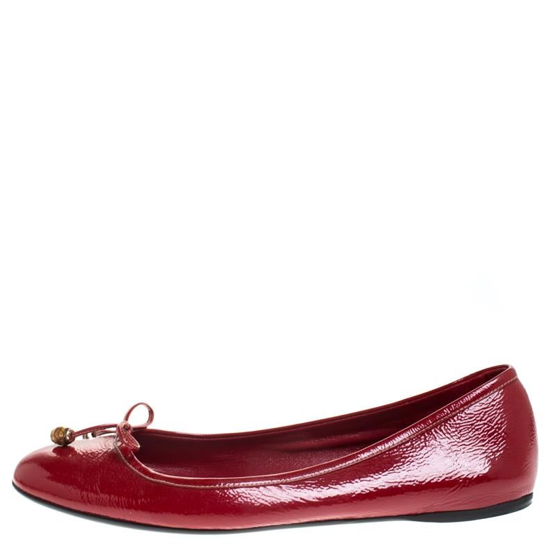 Nothing like a pretty pair of flats to be in high comfort and style! Crafted from red patent leather, this gorgeous Gucci pair features leather-lined insoles housing the brand's iconic label and bamboo-detailed bows perched on the round-toed vamps.


