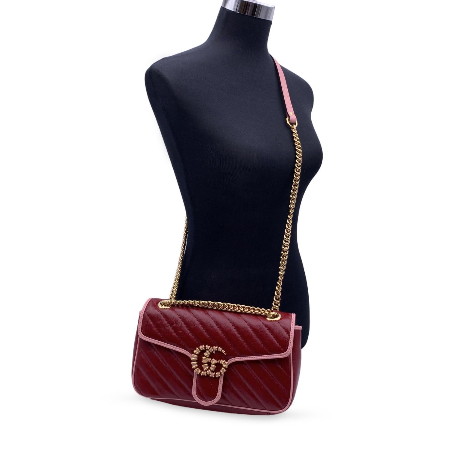 Beautiful Gucci GG Marmont Diagonal shoulder bag in red quilted leather.The bag features diagonal matelassé leather and pink leather trim. Gold metal double GG logo on the front with pink and red enamel. Flap with spring closure. Leather and gold