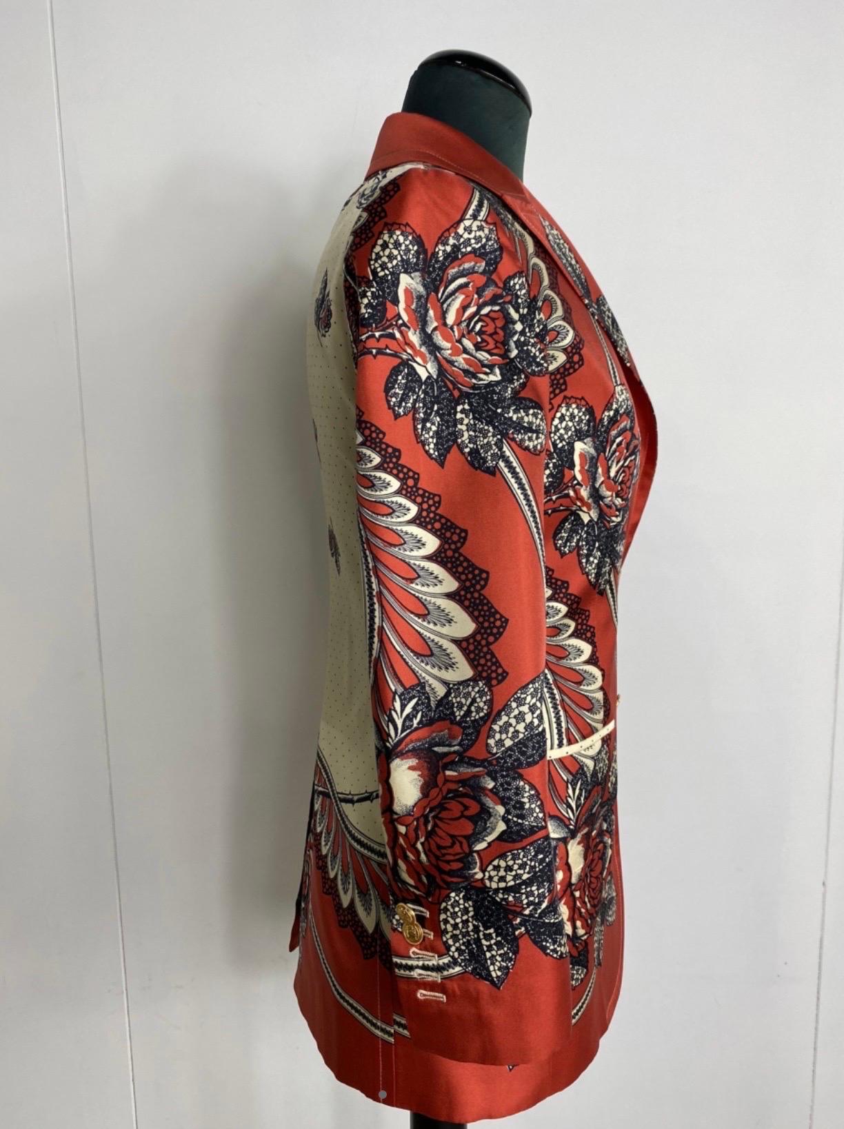 Gucci women's jacket.
in silk, red background color, with black and champagne-colored flowers printed, while the back has a champagne-colored background with black and red flowers and a central slit at the bottom, two pockets on the front of the
