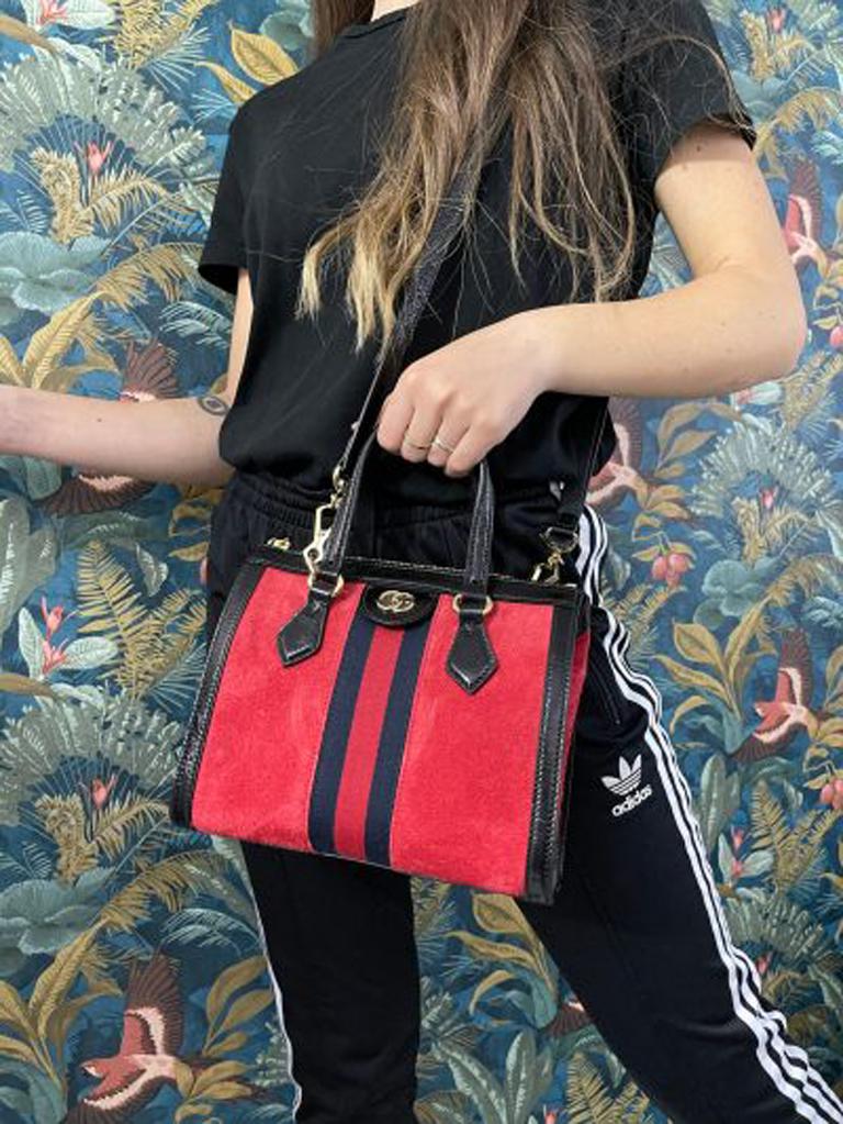 Gucci bag, Ophidia line, made in red suede with black leather details and golden hardware. Equipped with a zip closure. Equipped with double leather handle and a removable and adjustable shoulder strap in black leather. Internally lined in beige