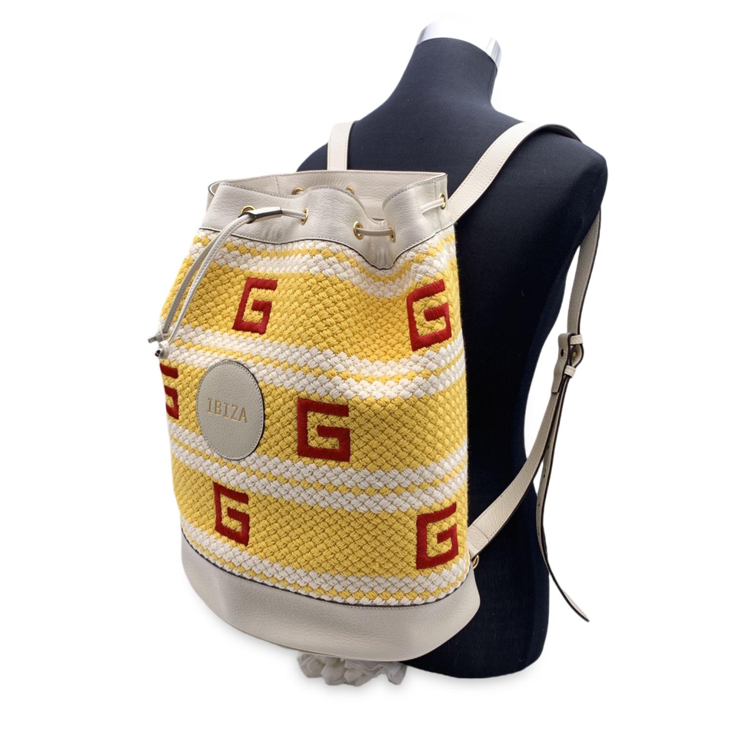 Gucci Limited Edition 'Ibiza' Backpack from the 2021 Resort collection.It features yellow and white woven fabric with red Square-G embroidery. White leather trim, handle and backstraps.'Ibiza' round leather patch on the front. Drawstring closure.
