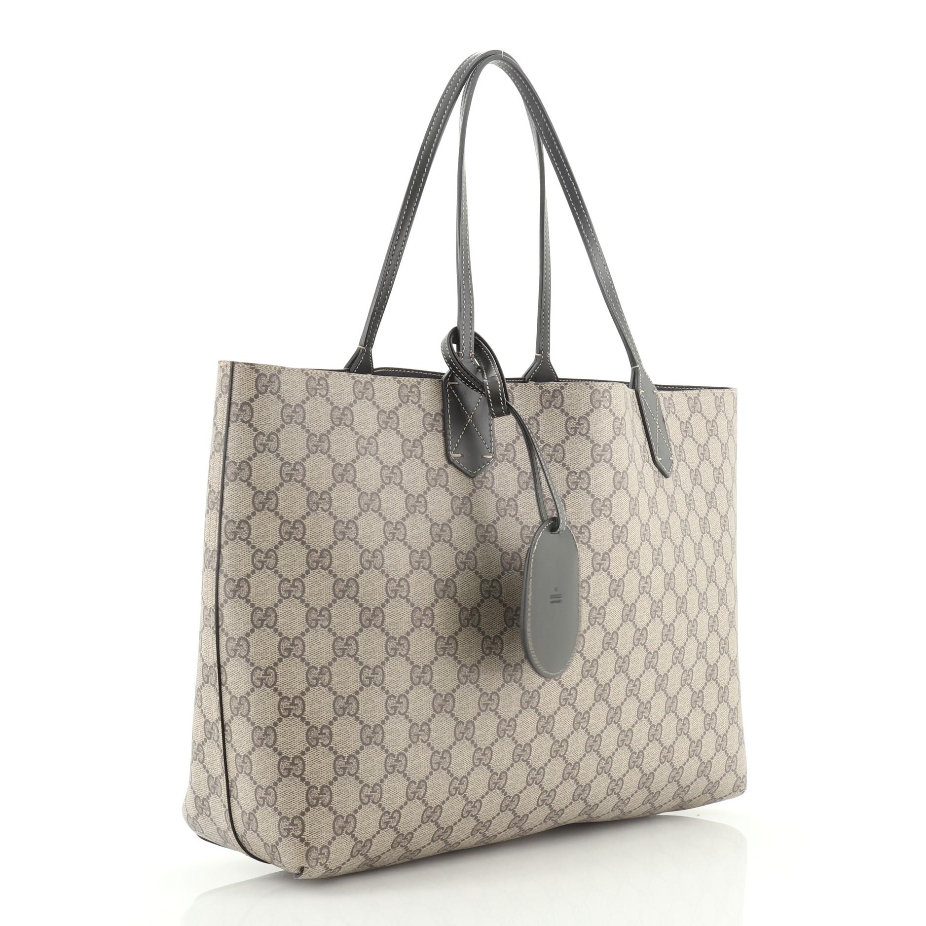 This Gucci Reversible Tote GG Print Leather Large, crafted from brown GG print leather, features dual flat leather handles. It opens to a reversible black leather interior. 

Condition: Excellent. Minor scuffs on handle wax edges, scratches on