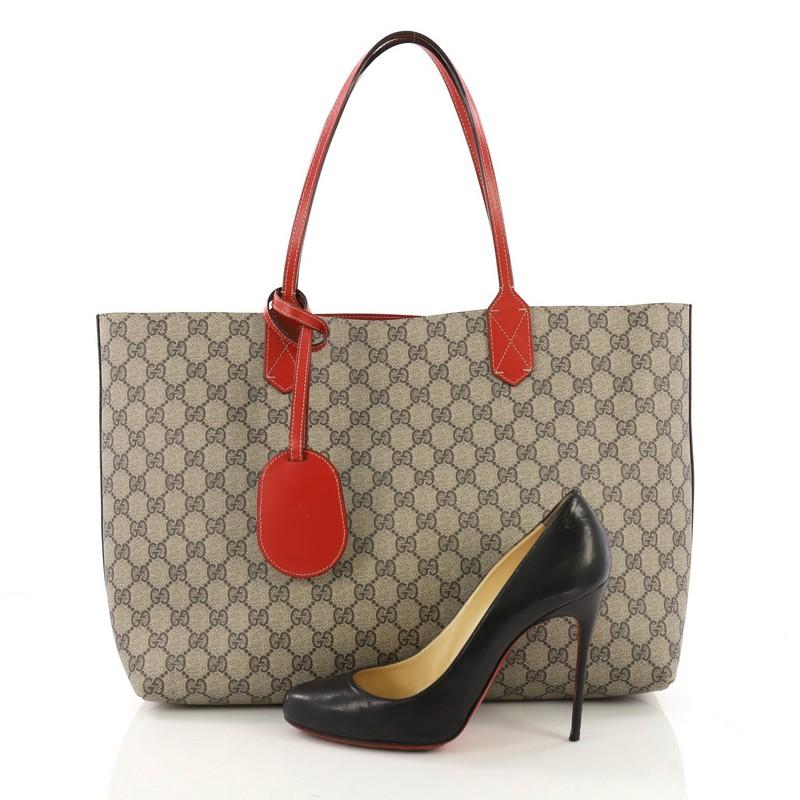 This Gucci Reversible Tote GG Print Leather Medium, crafted in brown GG coated canvas, features dual flat leather handles. It opens to a reversible red leather interior. **Note: Shoe photographed is used as a sizing reference, and does not come with